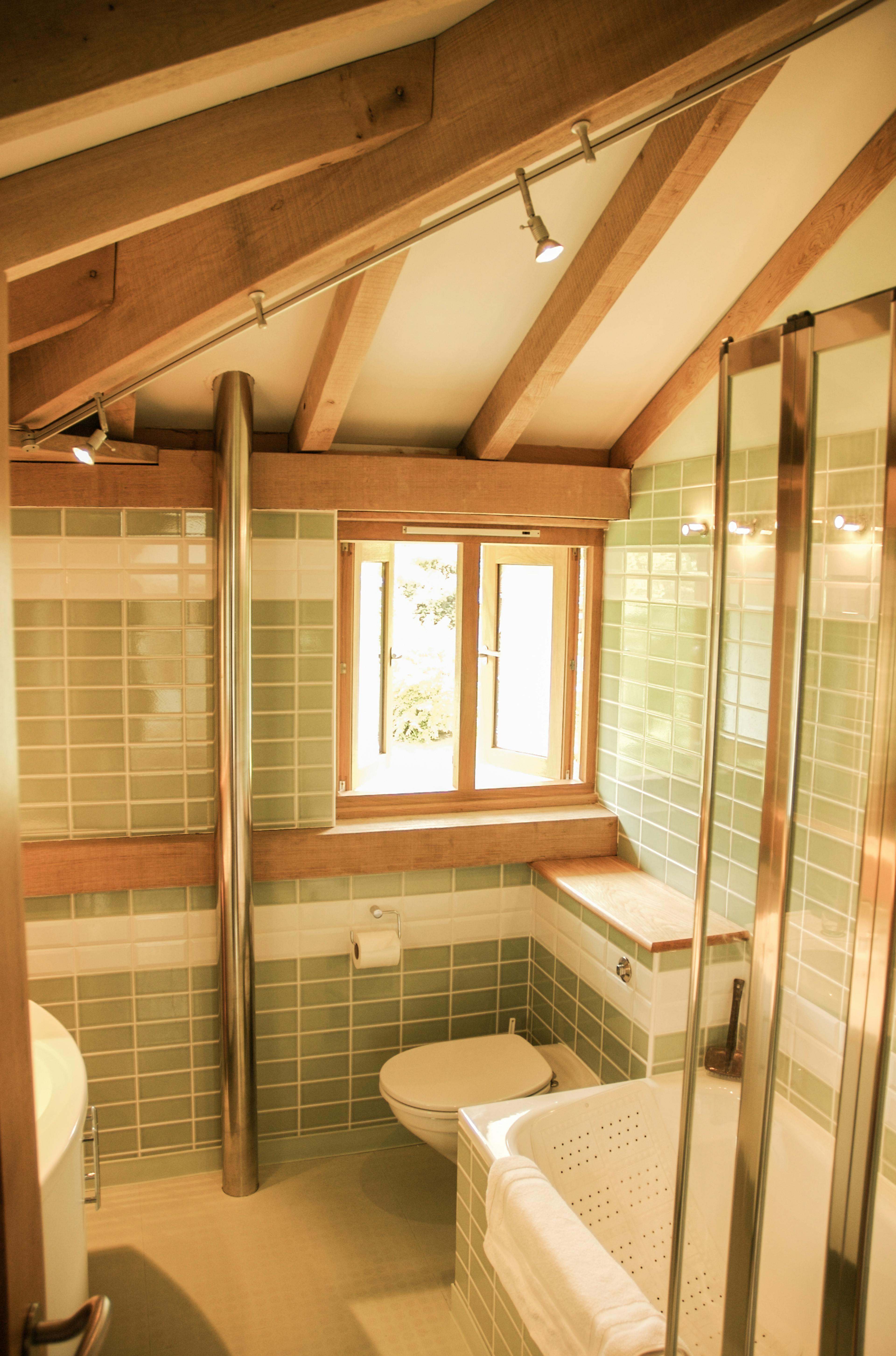 Interior view of a bathroom in an oak-framed house, showing exposed timber ceiling beams above a modern, minimalist space