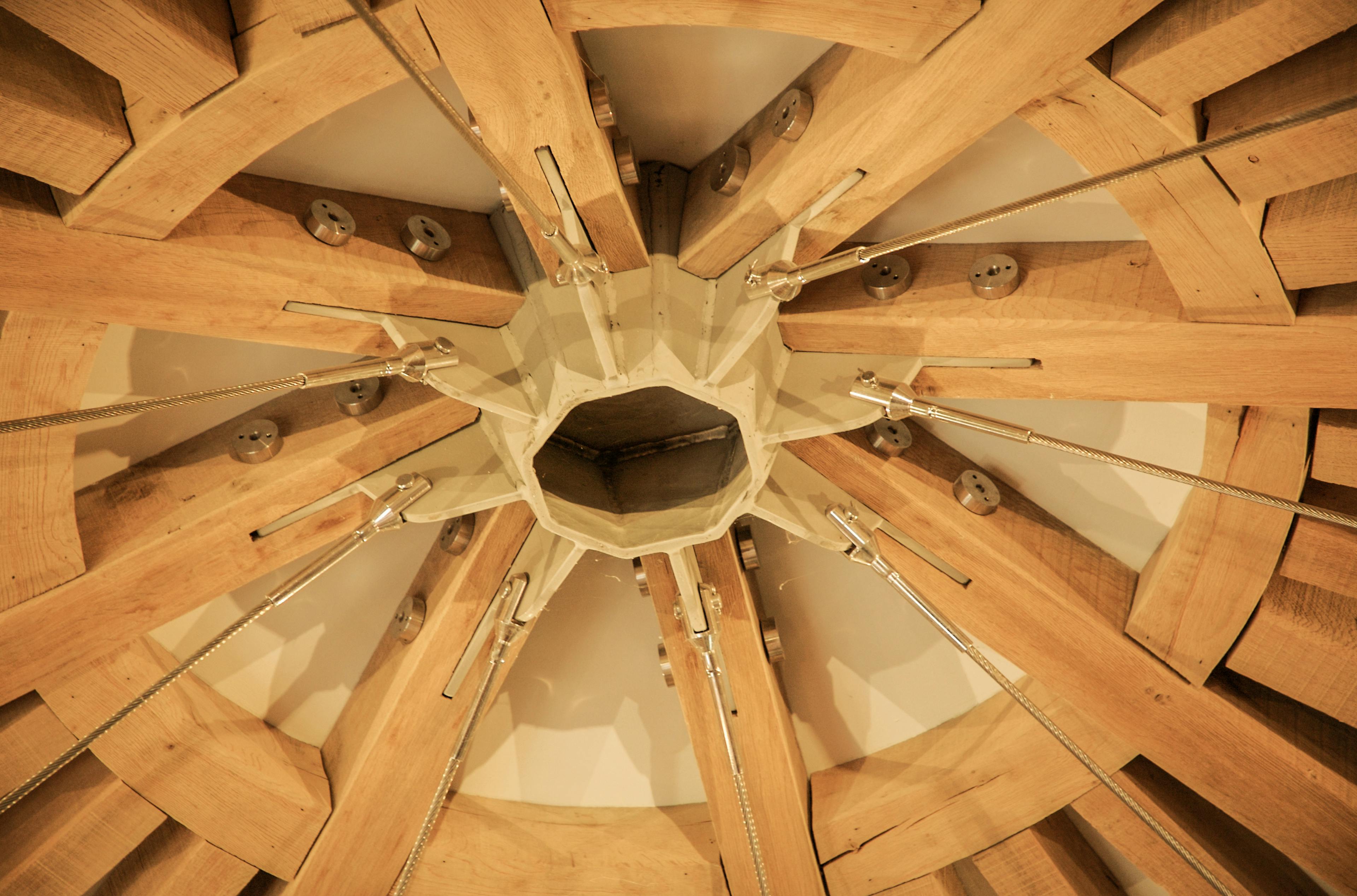Close-up of an interior structural detail in an oak-framed house, showing the connection between exposed timber beams and a steel joint element.