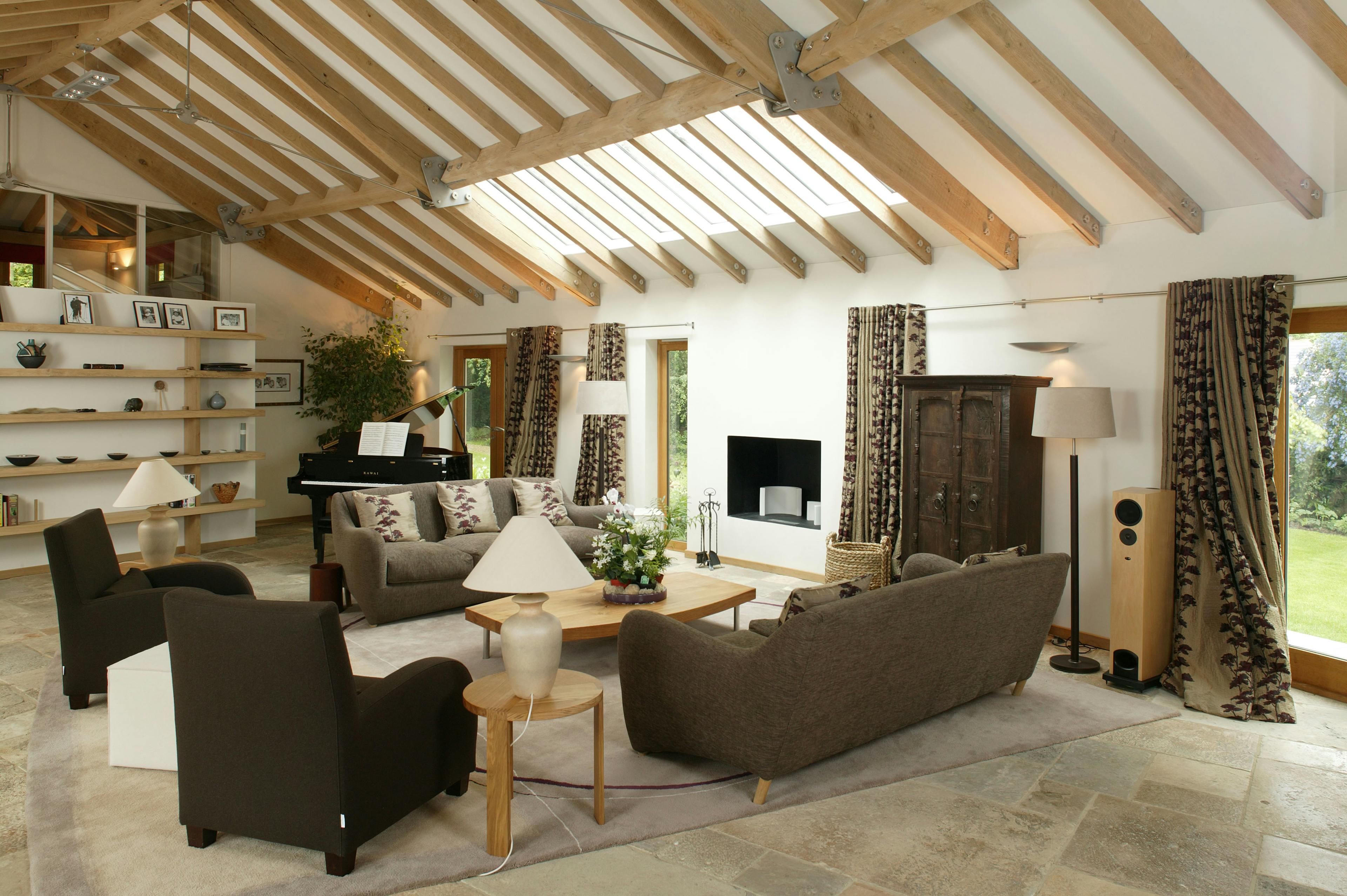 Finished interior of the living area in an oak-framed house, featuring exposed timber beams, comfortable seating, and natural light creating a warm and inviting atmosphere