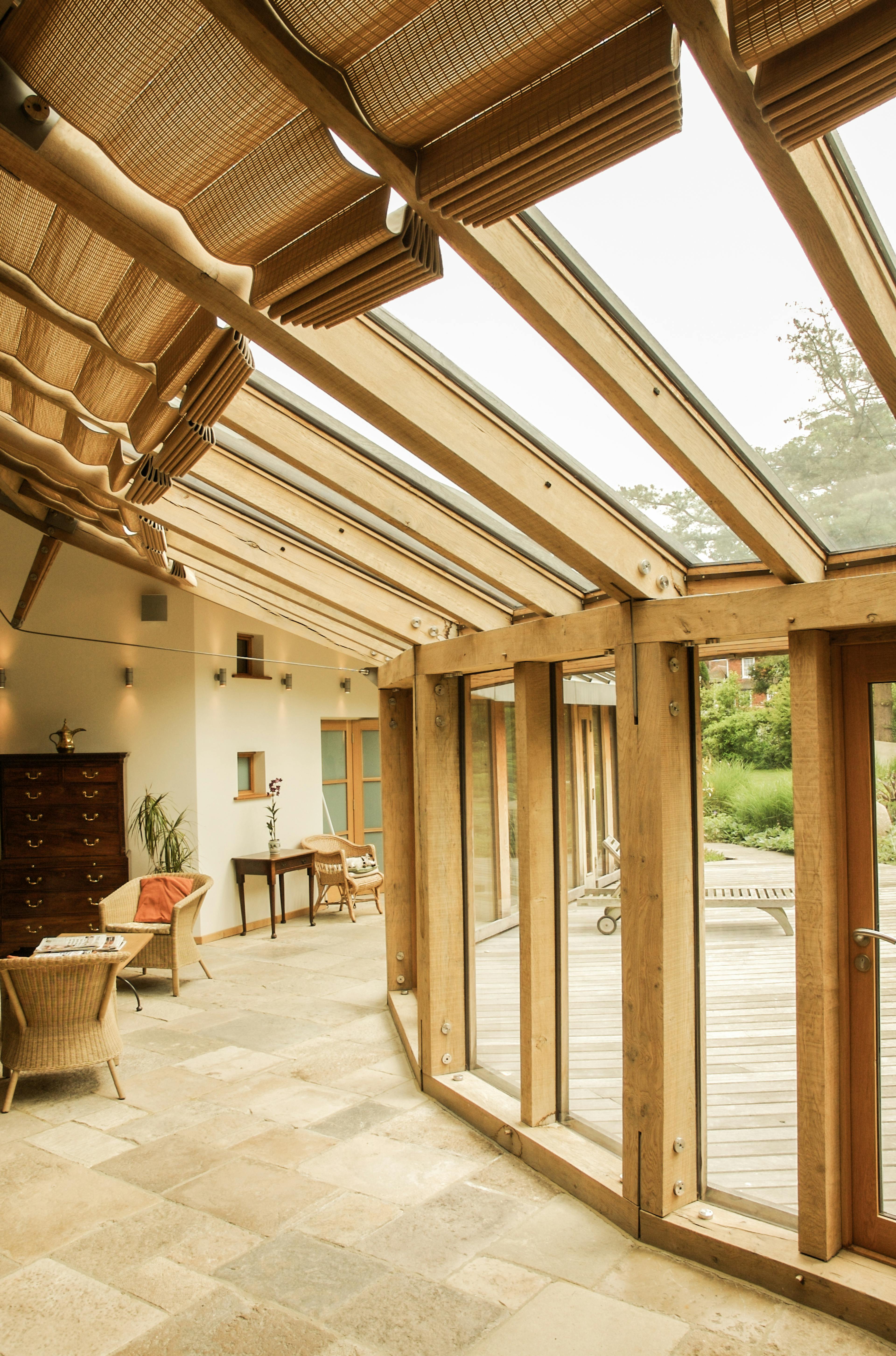 Interior view of a walkway in an oak-framed house, featuring detailed glazing connections between large glass panels and timber framing