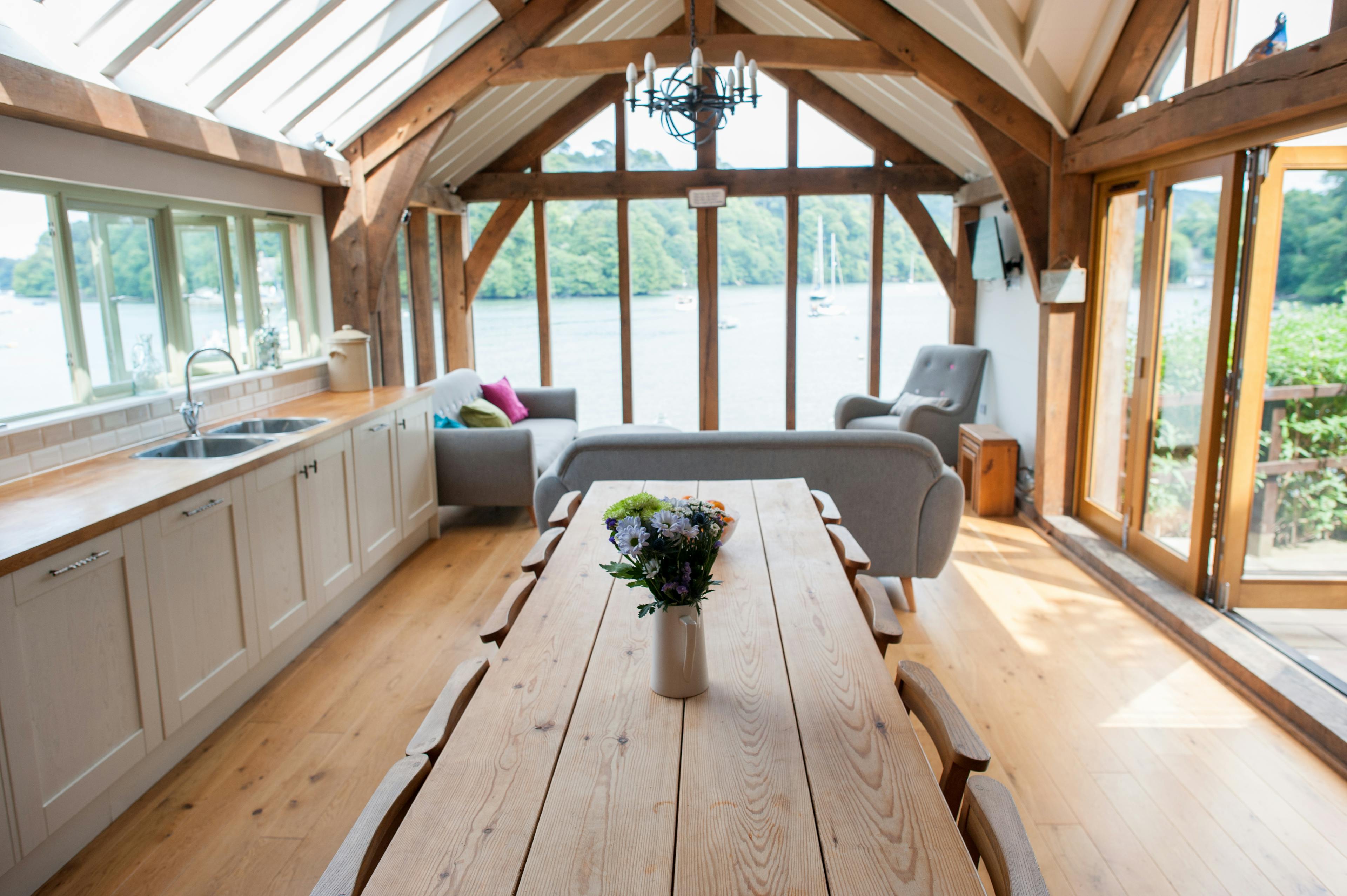 Interior view of a finished coastal cottage living space, featuring exposed oak beams, natural light, and views toward the water