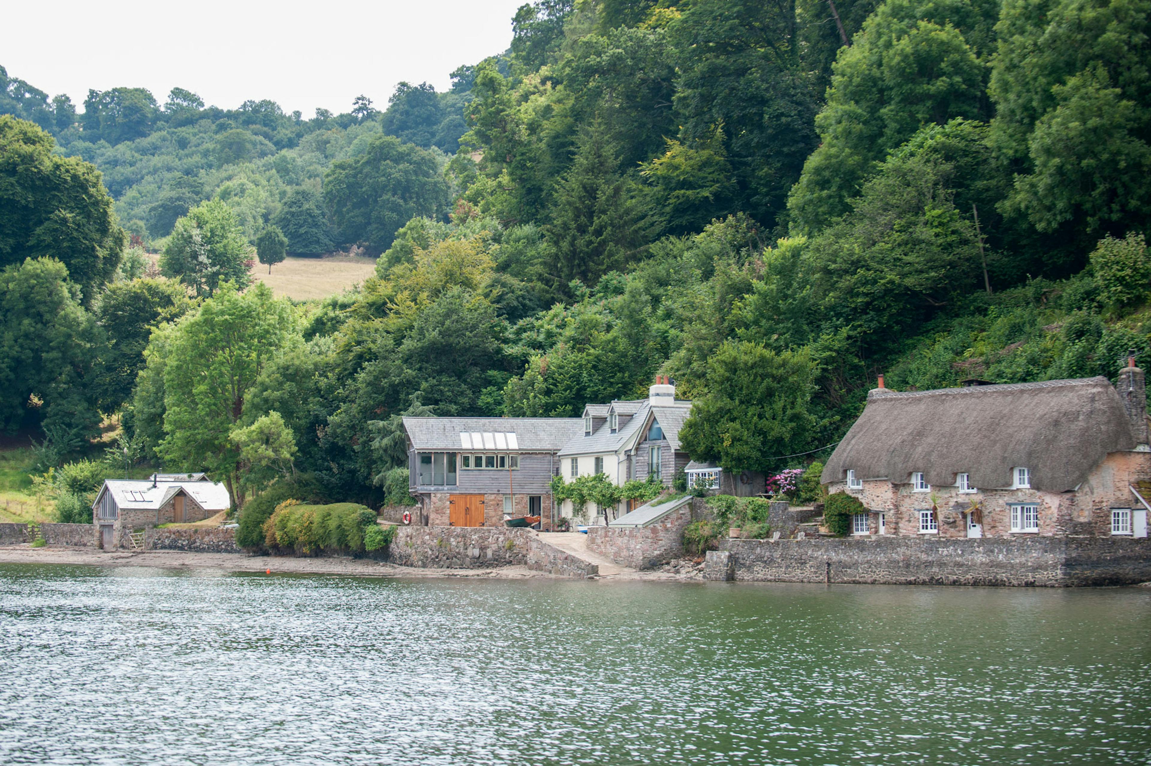 Exterior view of a finished oak-framed cottage overlooking a coastal estuary, with natural timber detailing and scenic waterfront surroundings