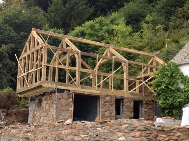 On-site assembly of an oak timber frame at a coastal cottage, showing exposed beams and structural elements during construction