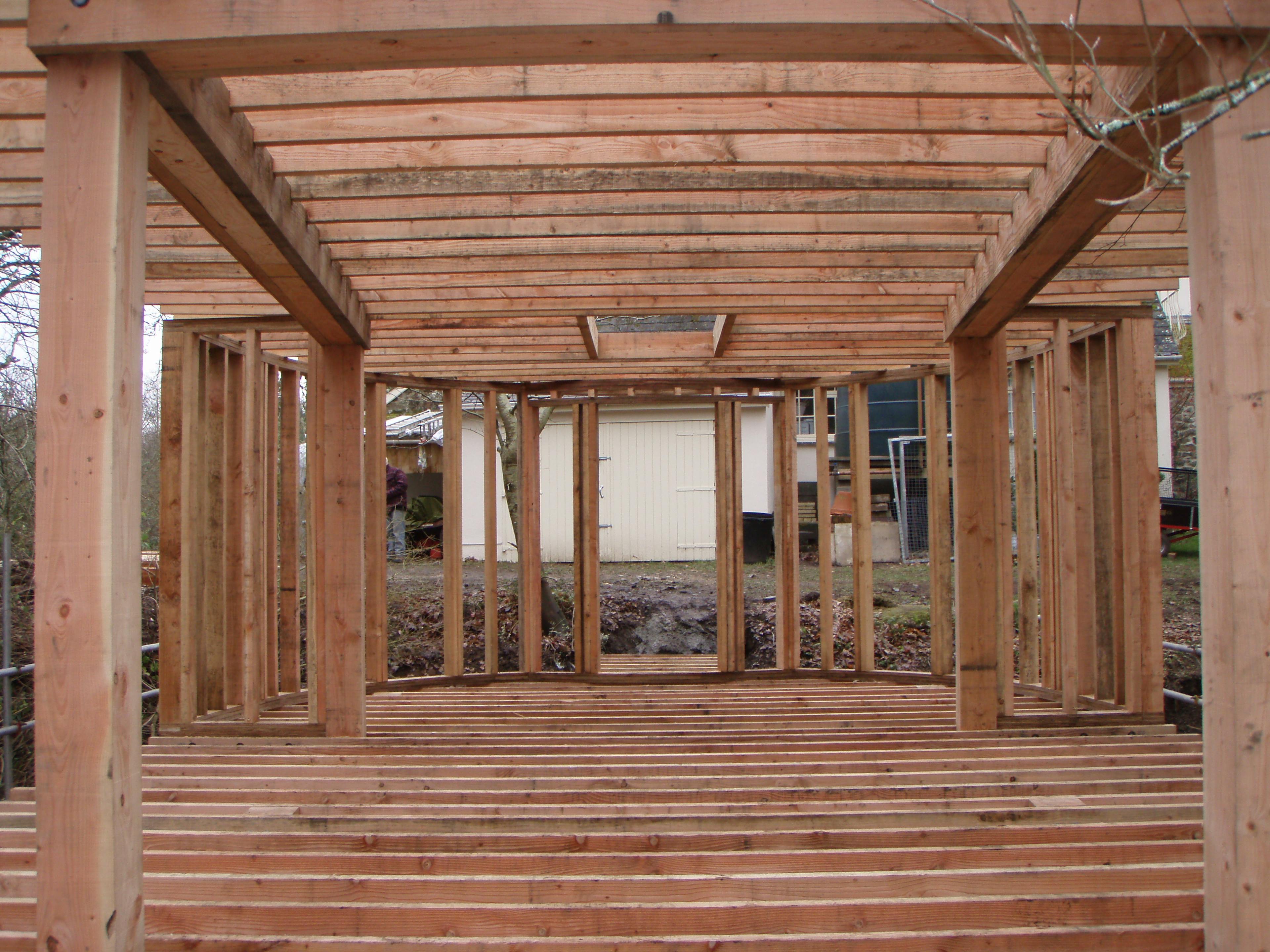 Interior view of a treehouse under construction in Dartmoor, featuring Douglas fir timber beams being assembled to form the structural framework