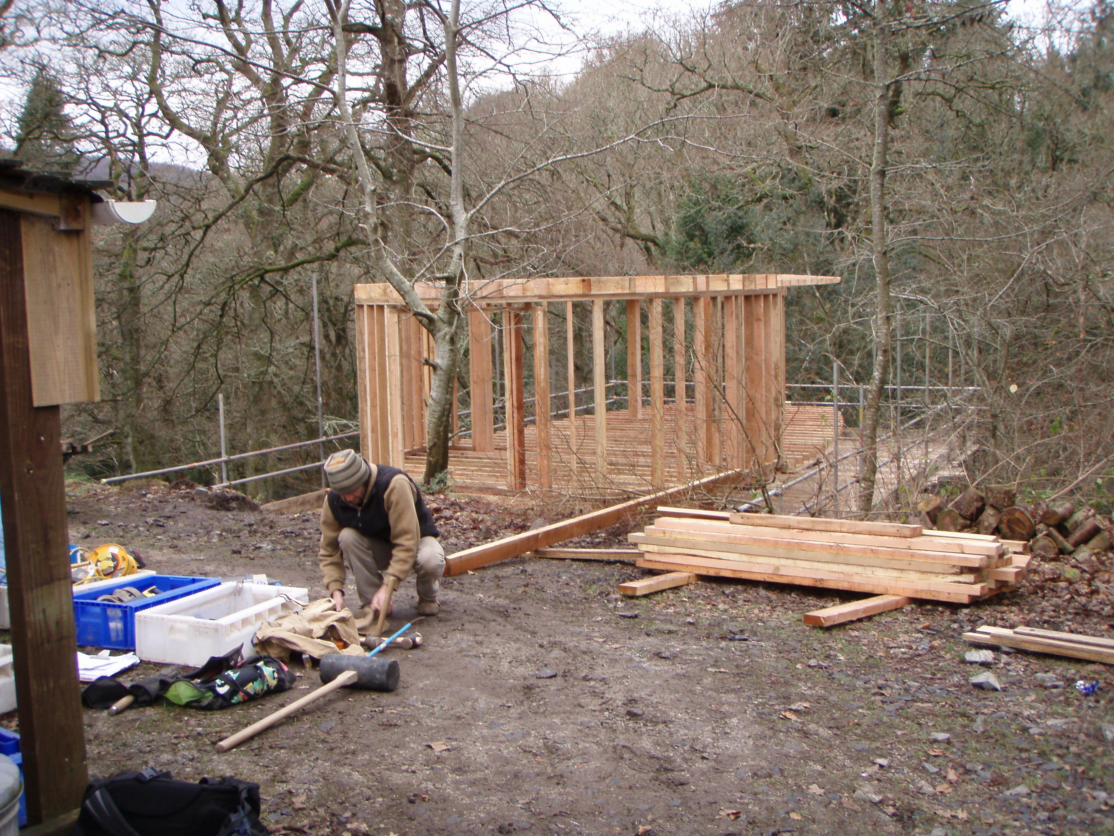 Construction site of a treehouse in Dartmoor showing the assembly of a Douglas fir timber structure with exposed beams and framework