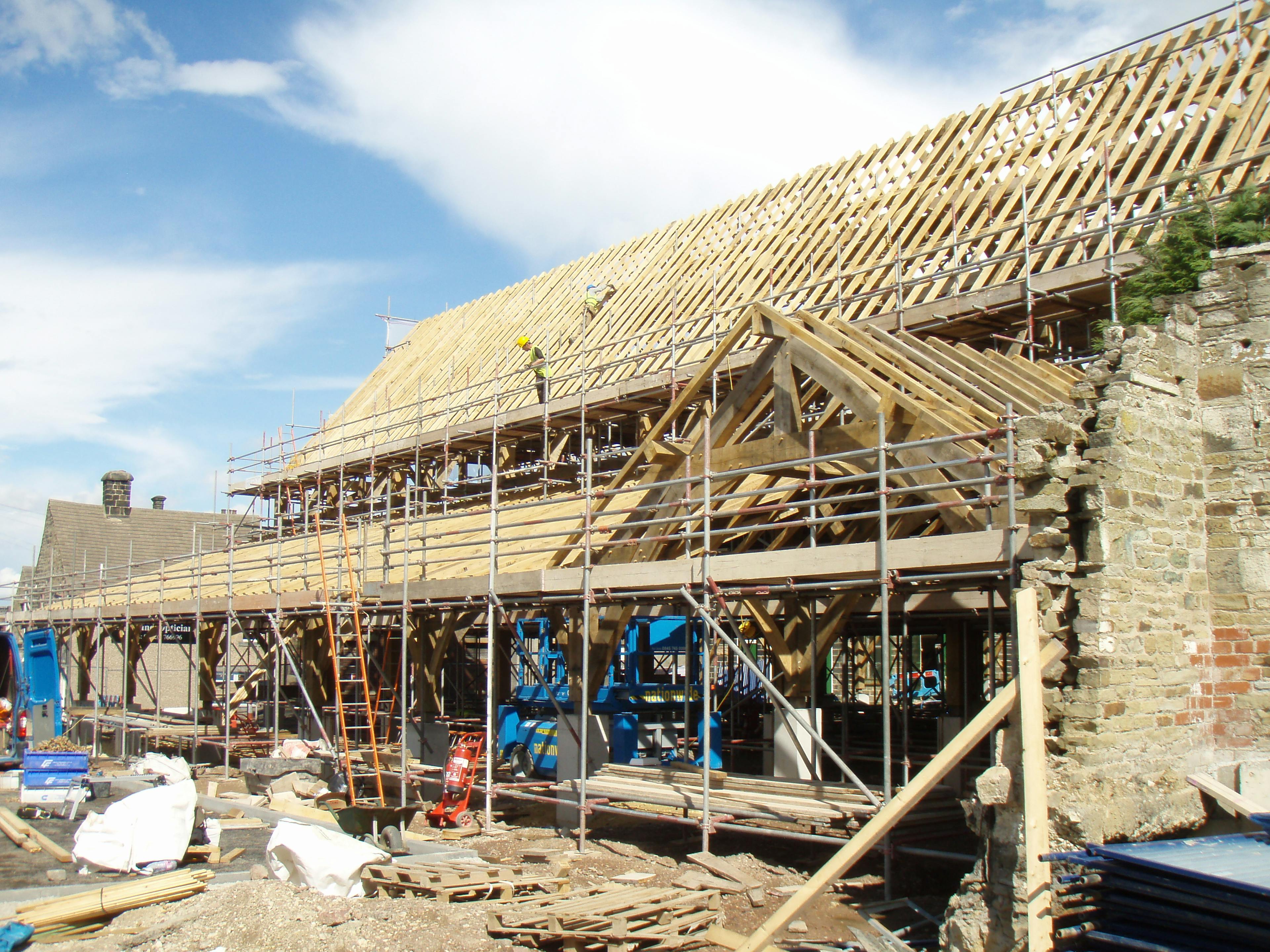 On-site assembly of an oak-framed entrance structure for the Penistone Market project, with exposed beams and scaffolding visible during construction