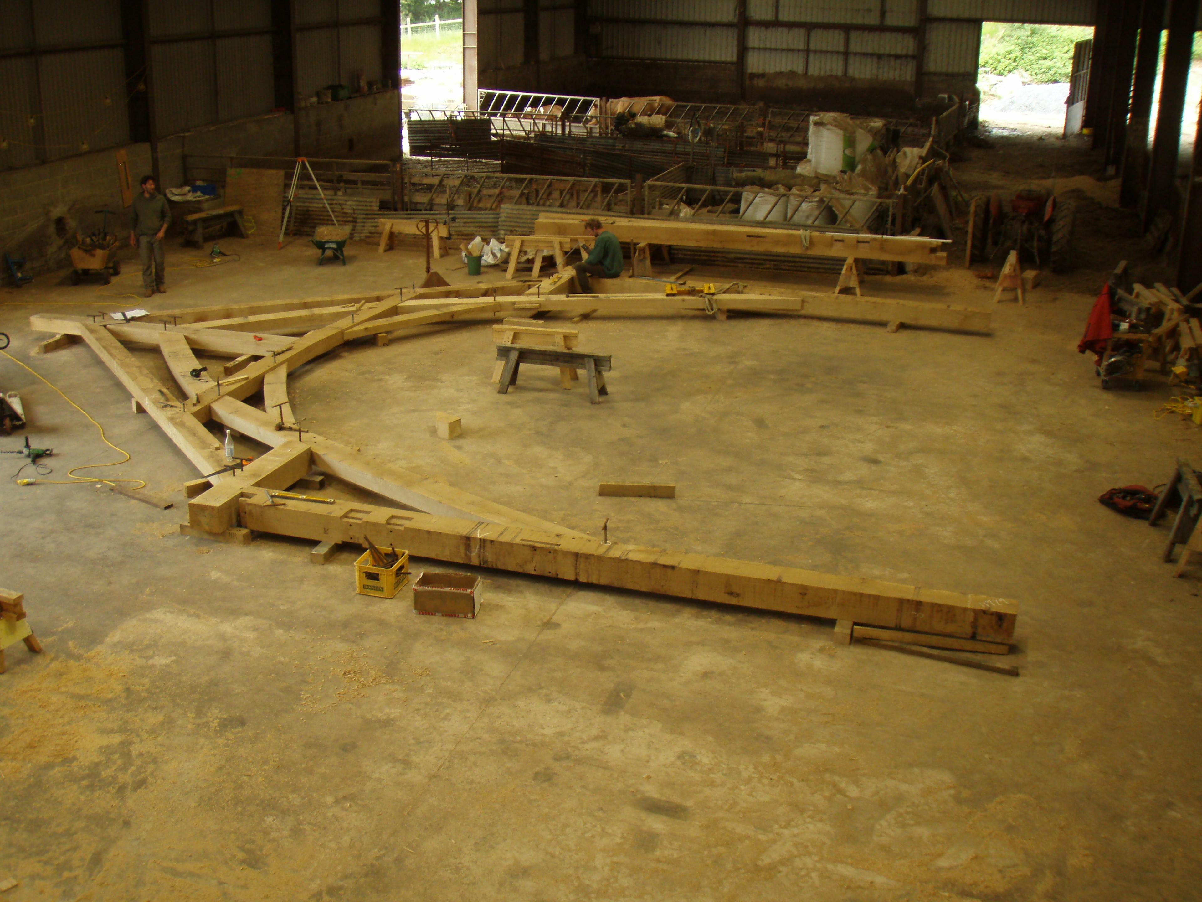 Workshop scene showing carpenters assembling a large oak roof truss for the Penistone Market construction project