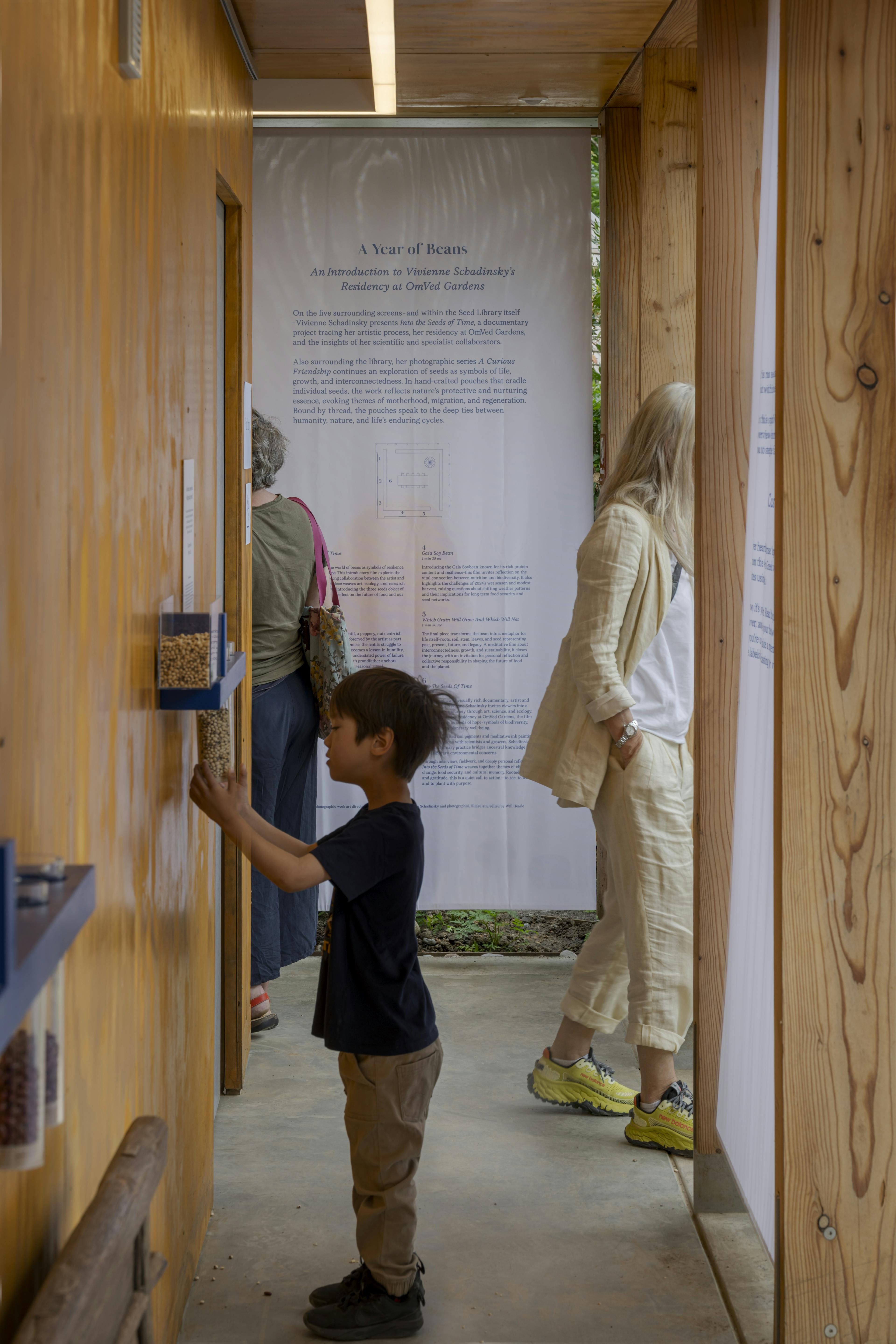 Children walking along a pathway beside a Douglas fir timber-framed event structure, surrounded by landscaped gardens and natural outdoor setting