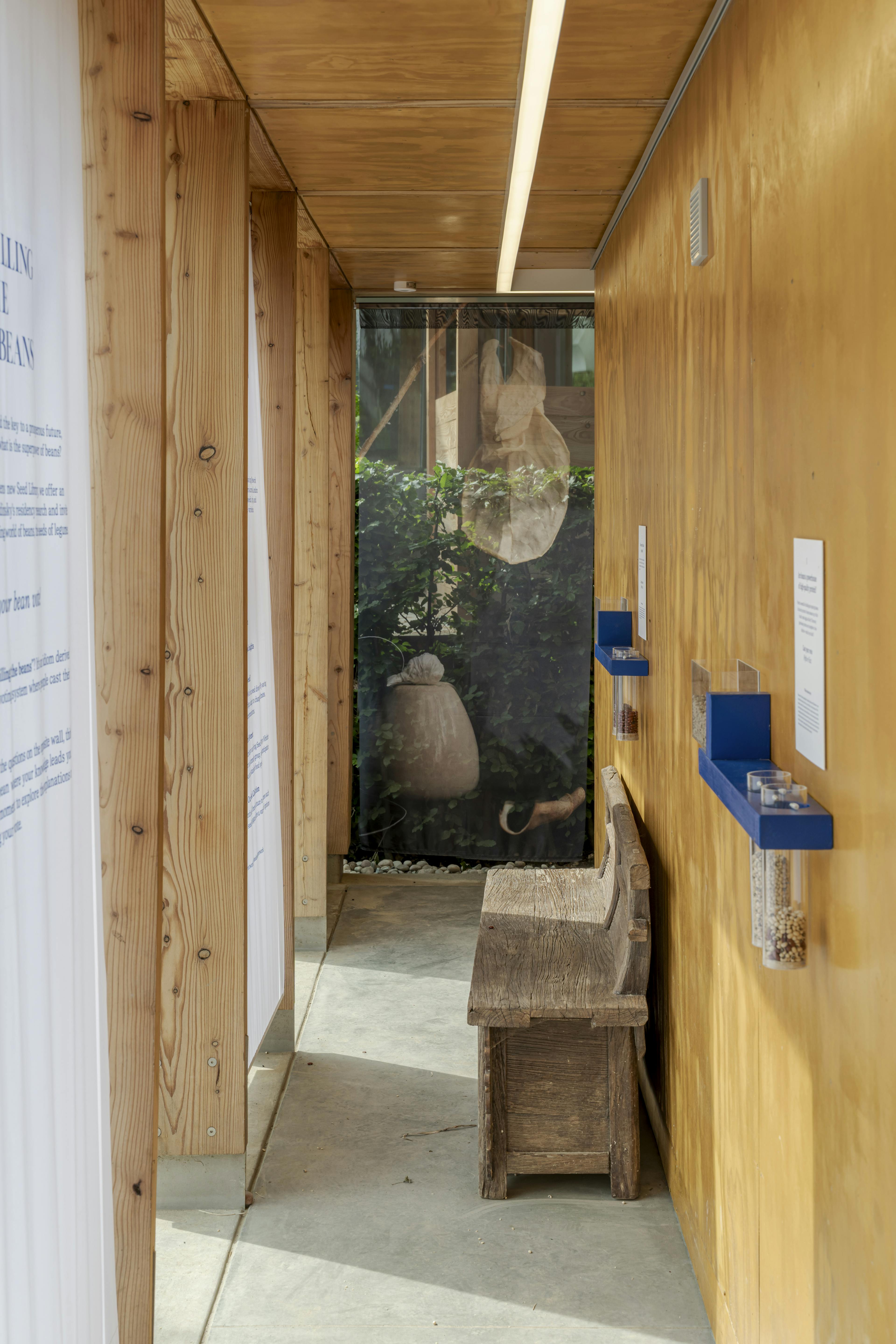 Exterior view of a Douglas fir timber-framed event structure with an adjacent walkway, set within landscaped gardens under natural daylight