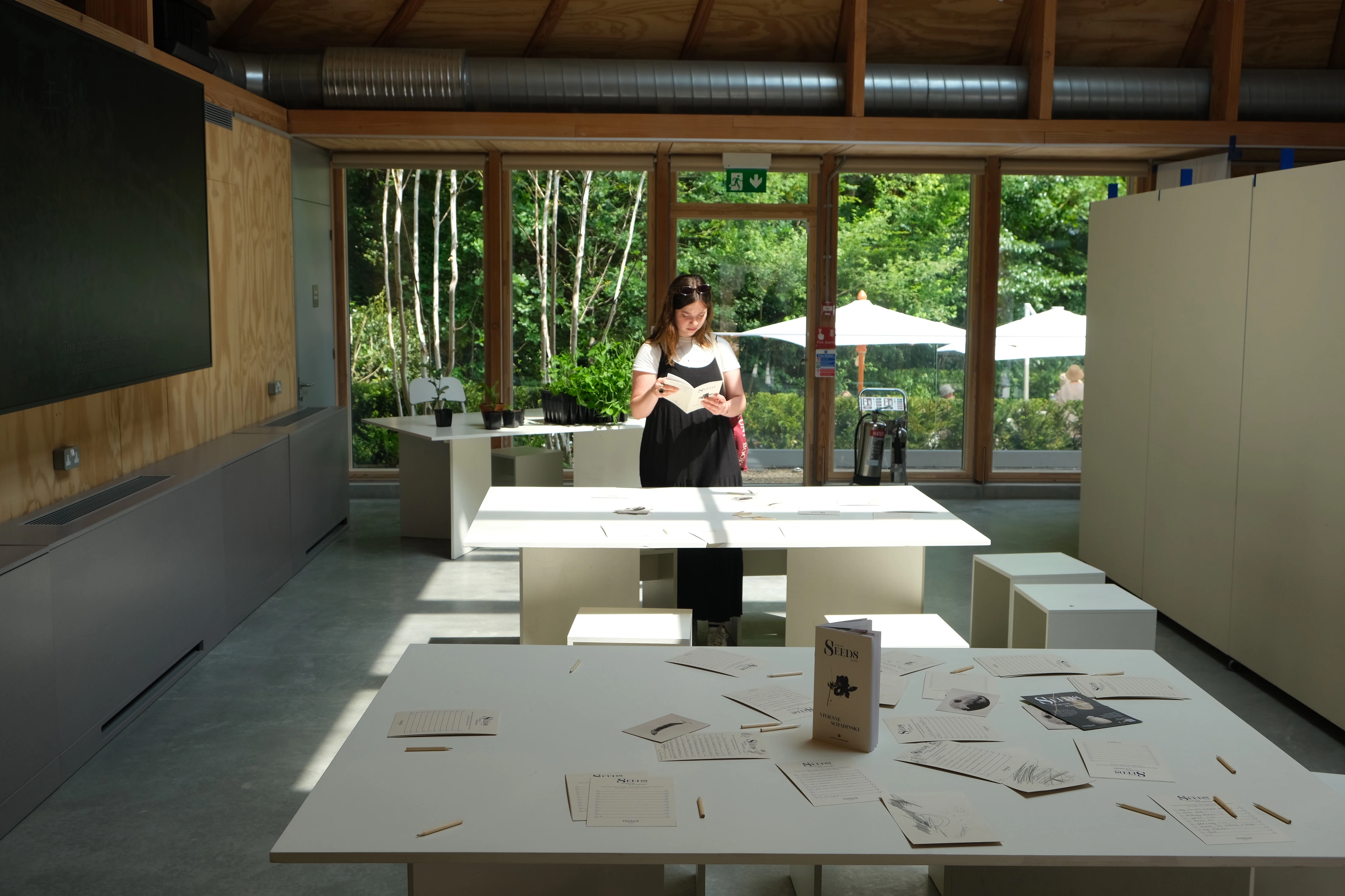 Interior of a timber-framed venue set up for a workshop, with natural light streaming in, wooden beams exposed, and simple furnishings arranged for group activity