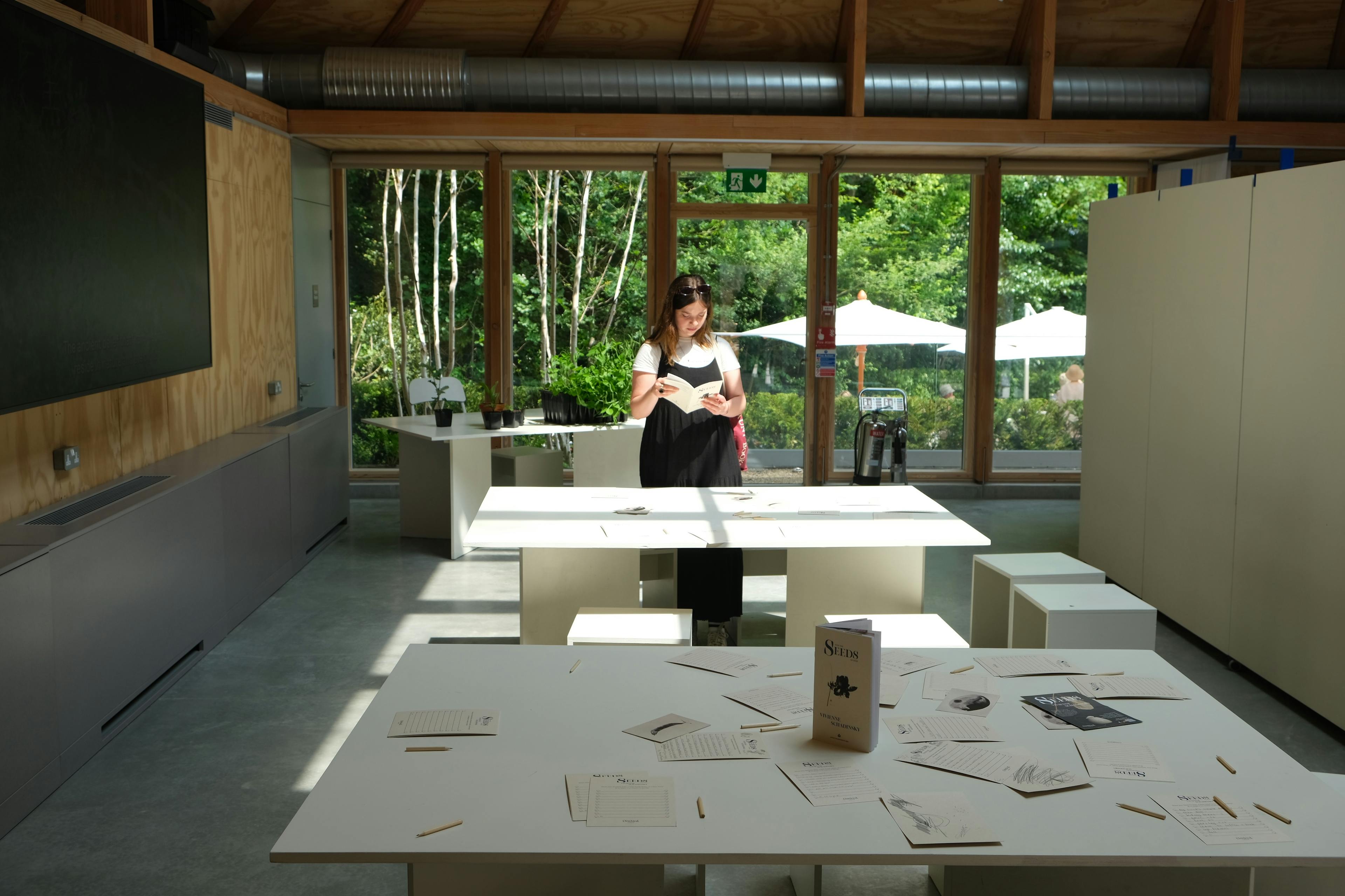 Interior of a timber-framed venue set up for a workshop, with natural light streaming in, wooden beams exposed, and simple furnishings arranged for group activity