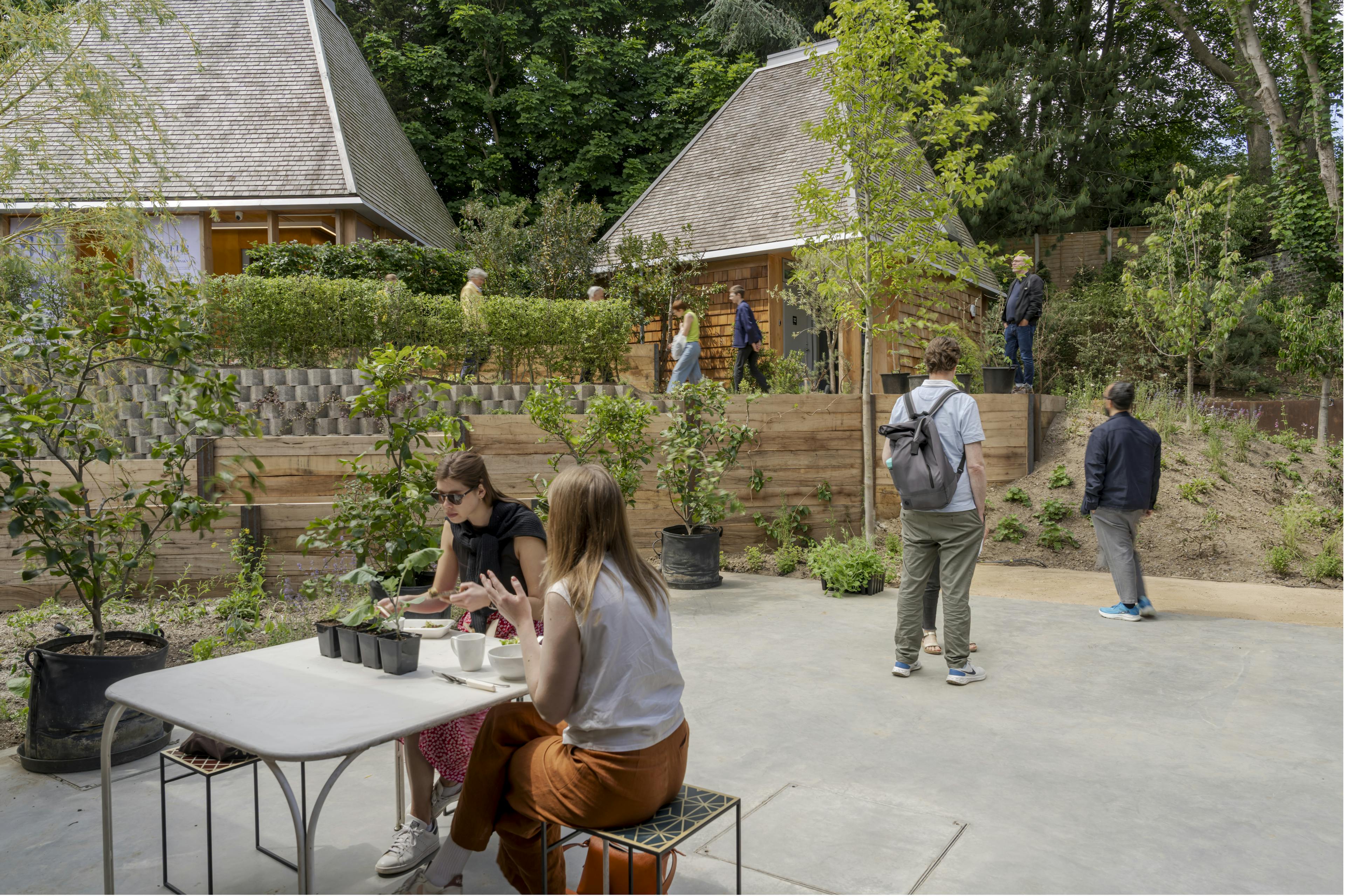 Exterior of a Douglas fir-framed building surrounded by gardens, with outdoor seating arranged for an event in a natural, landscaped setting