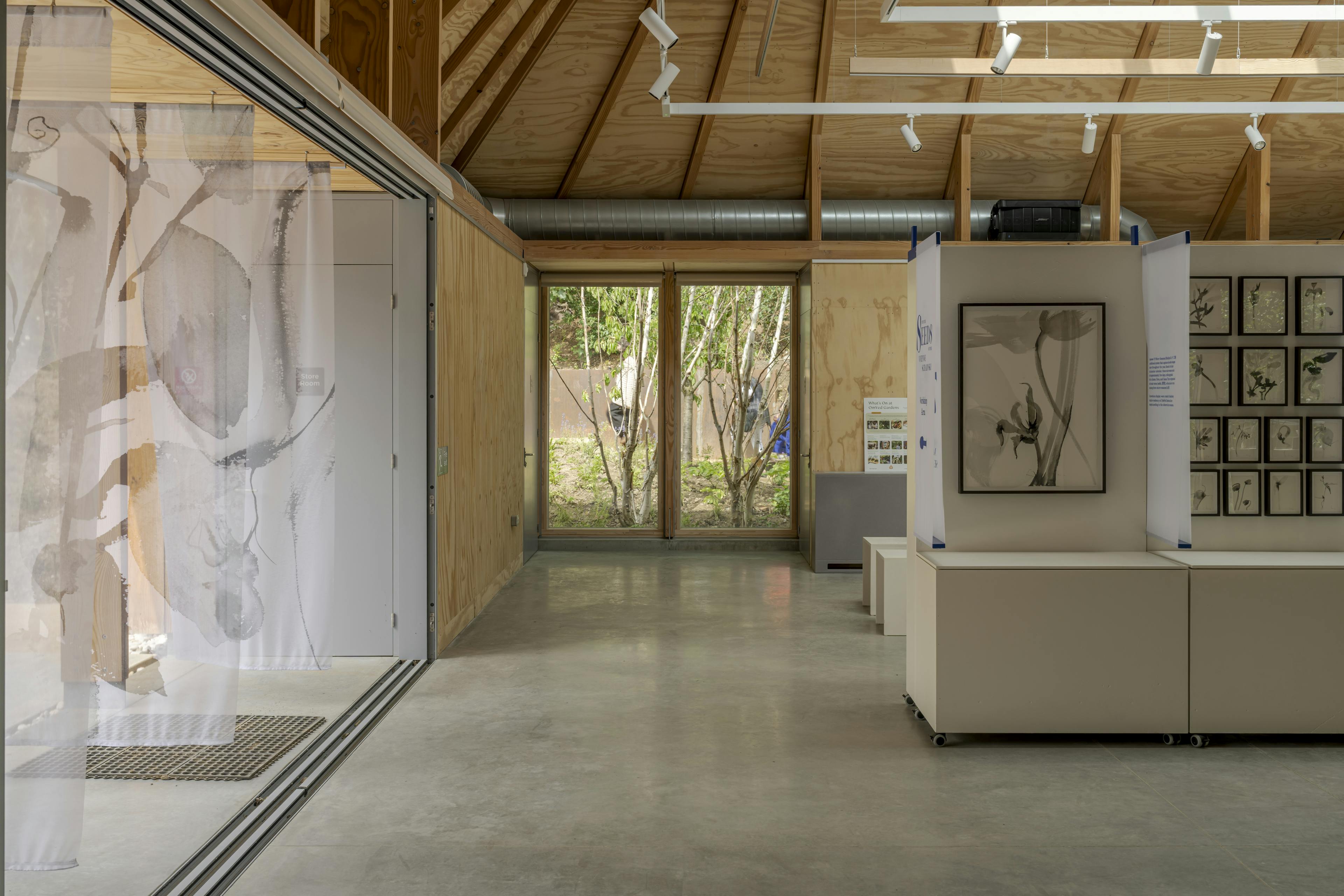 Interior of a Douglas fir-framed event space featuring a vaulted glazed ceiling and open-plan design, set up for seminars and exhibitions
