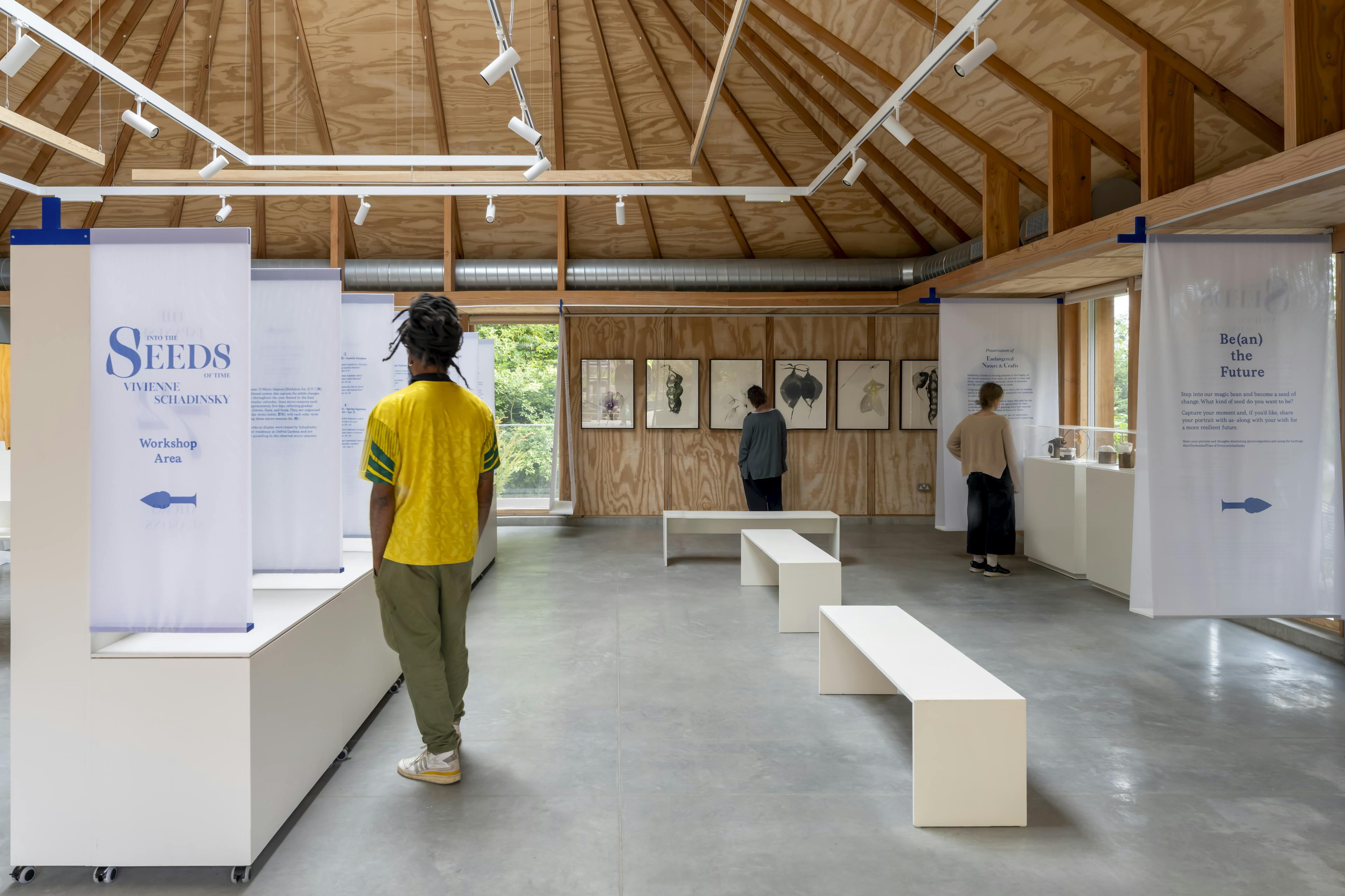Interior of a timber-framed event space with Douglas fir beams, hosting a public seminar and exhibition with people gathered inside