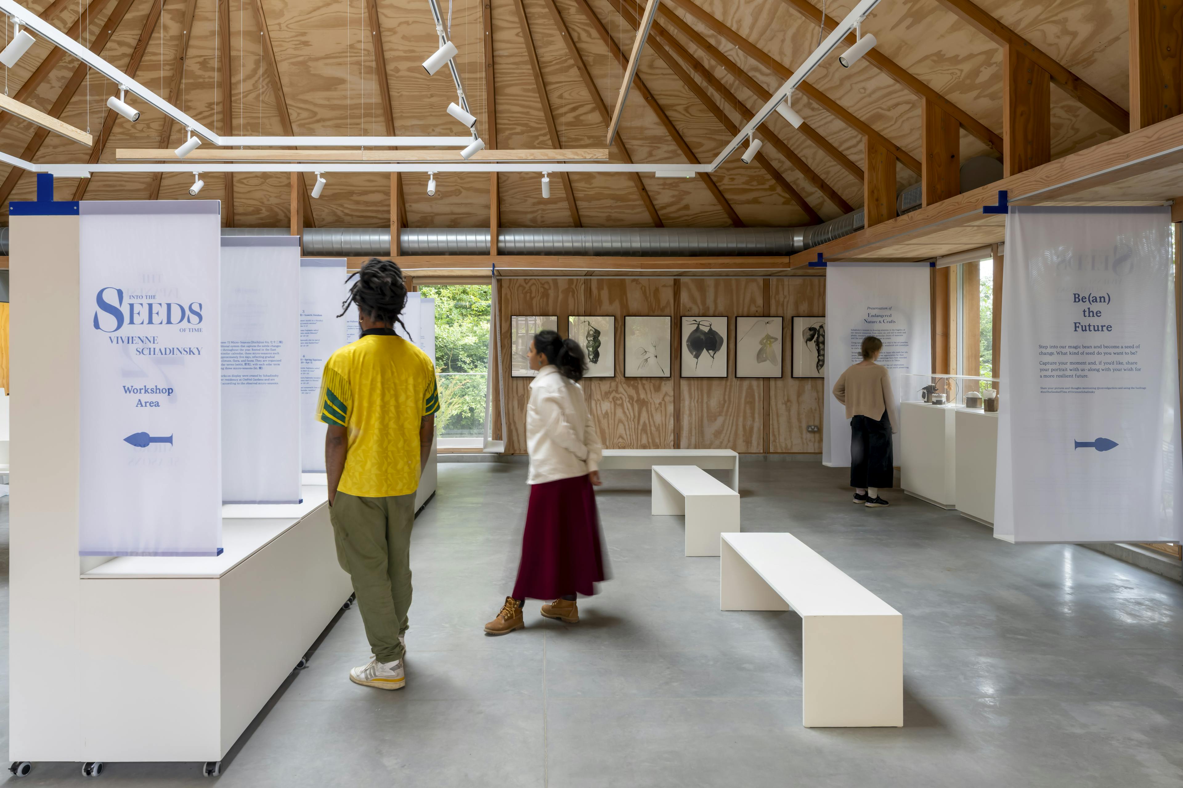 Interior of a Douglas fir-framed event space set up for a public seminar and exhibition, featuring exposed timber beams and attendees
