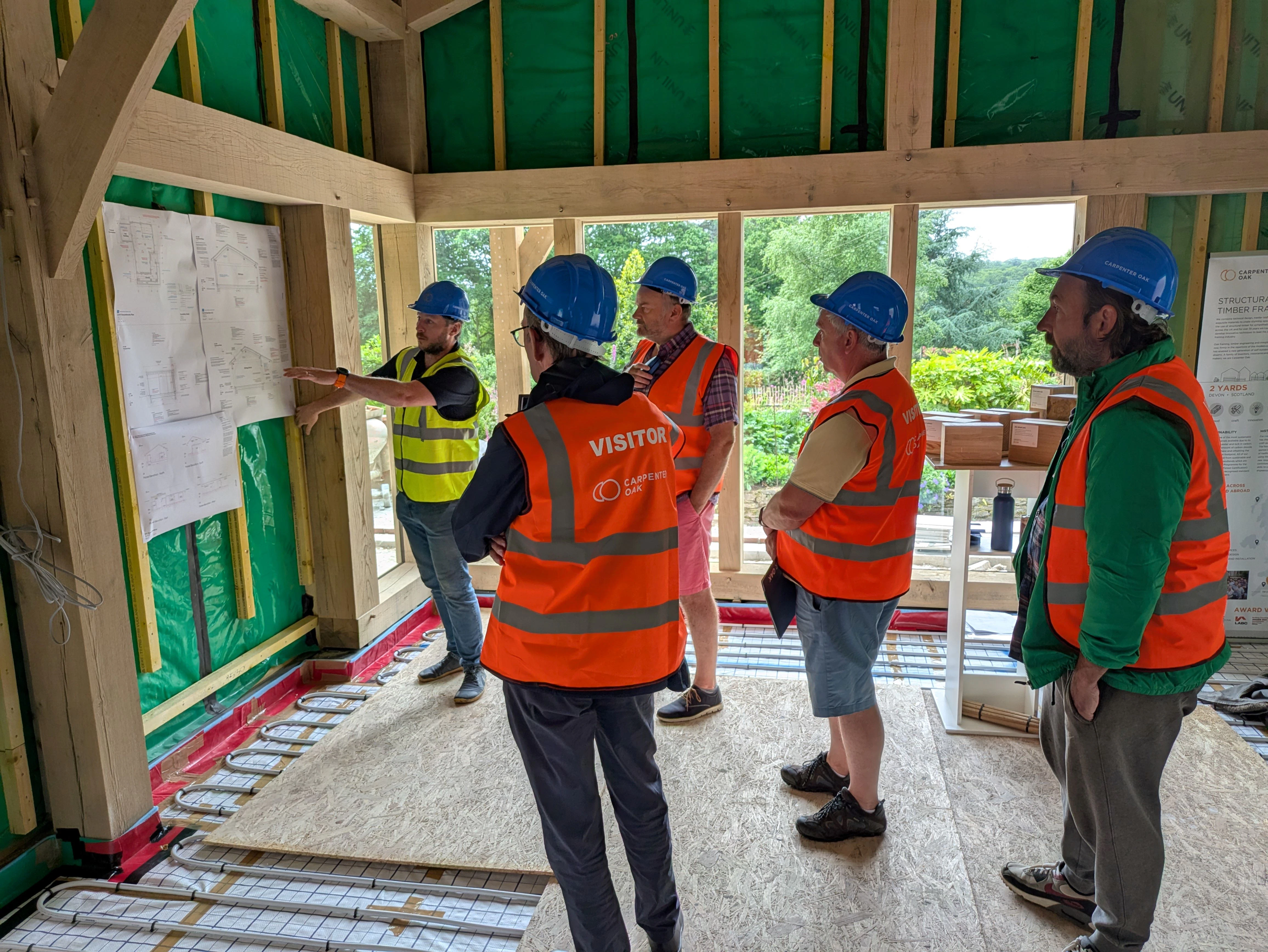People on a tour of an oak frame during the construction phase