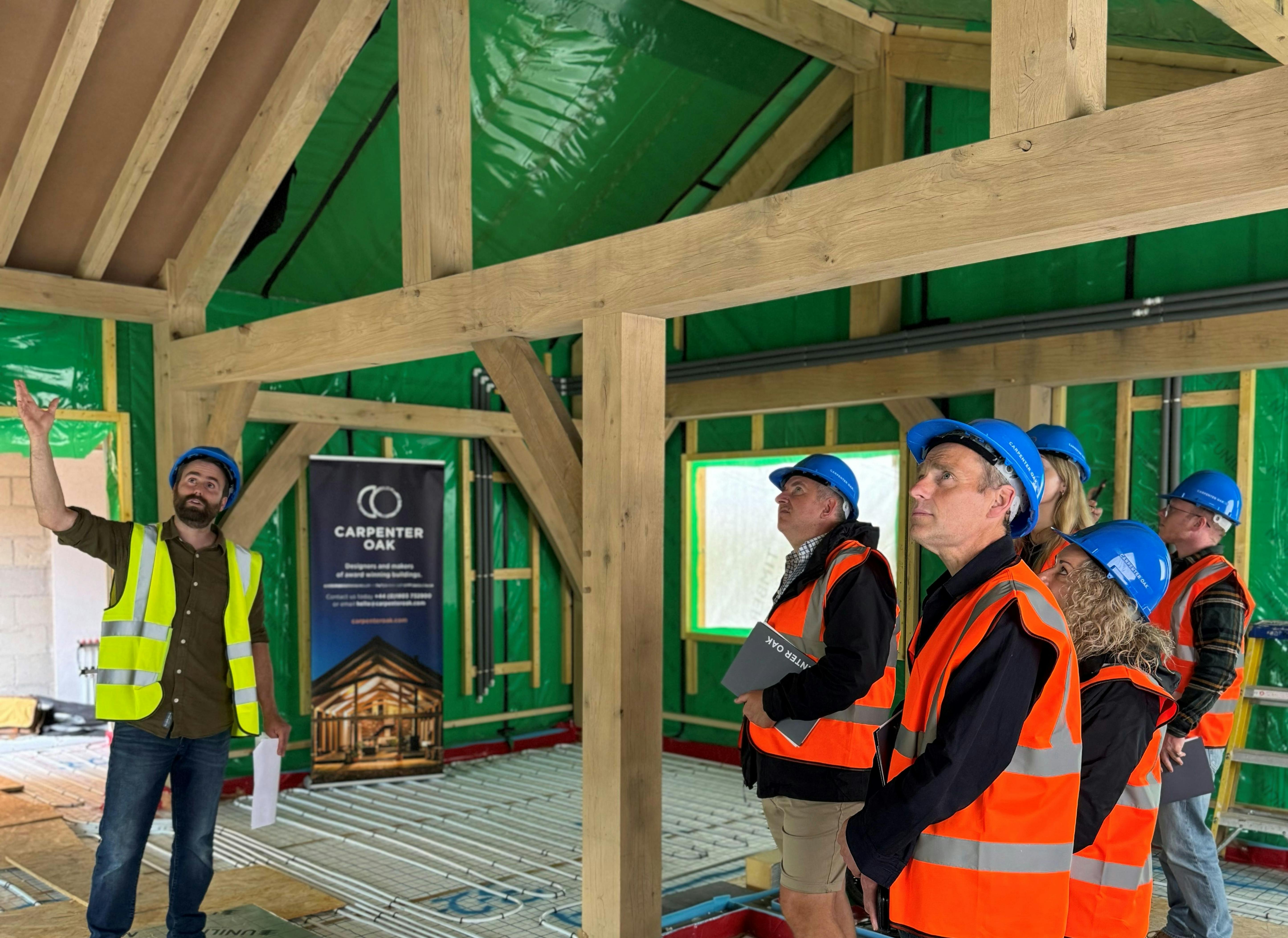People on a tour of an oak frame during the construction phase