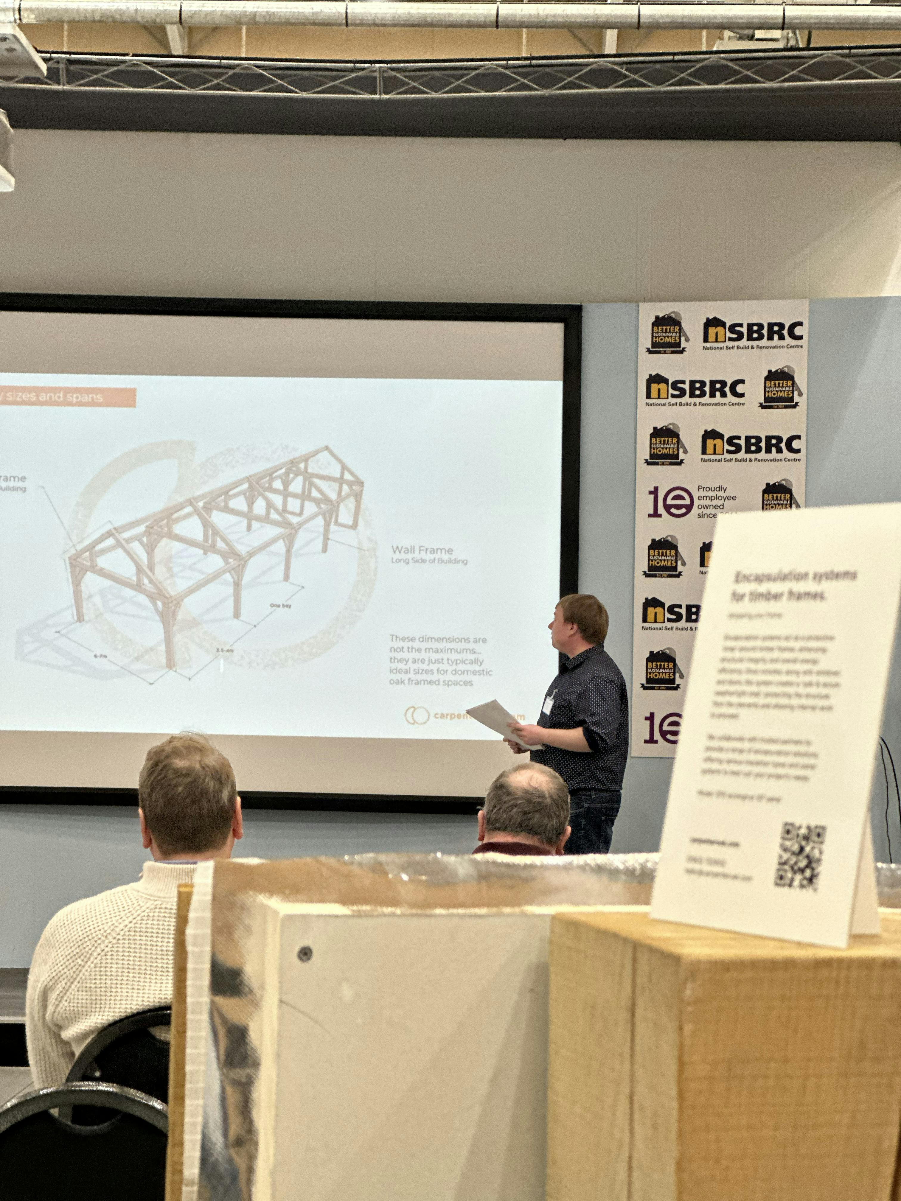 A presenter on a stage talking about oak frames