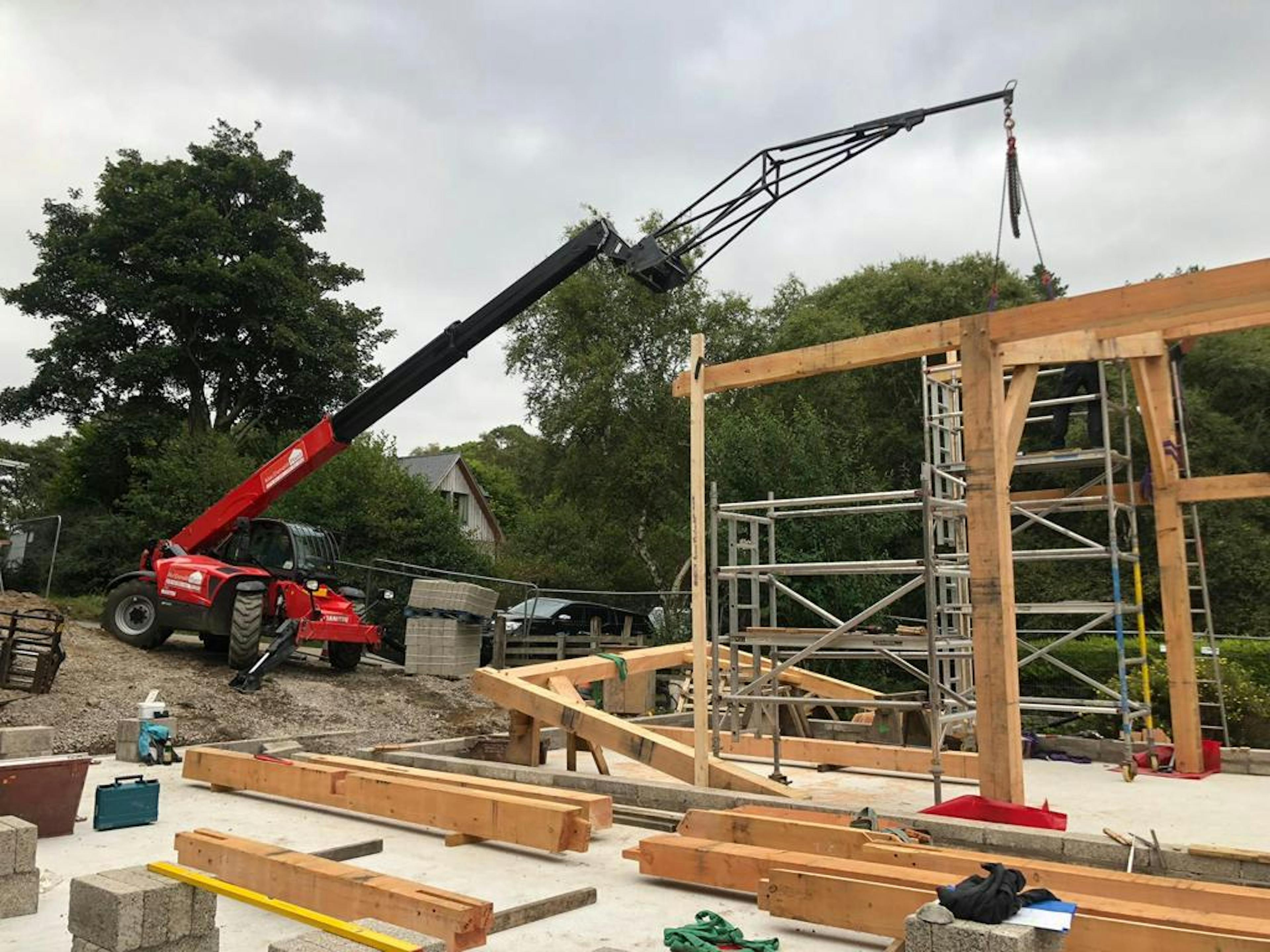 A crane lifting a piece of Douglas fir frame during construction of a home