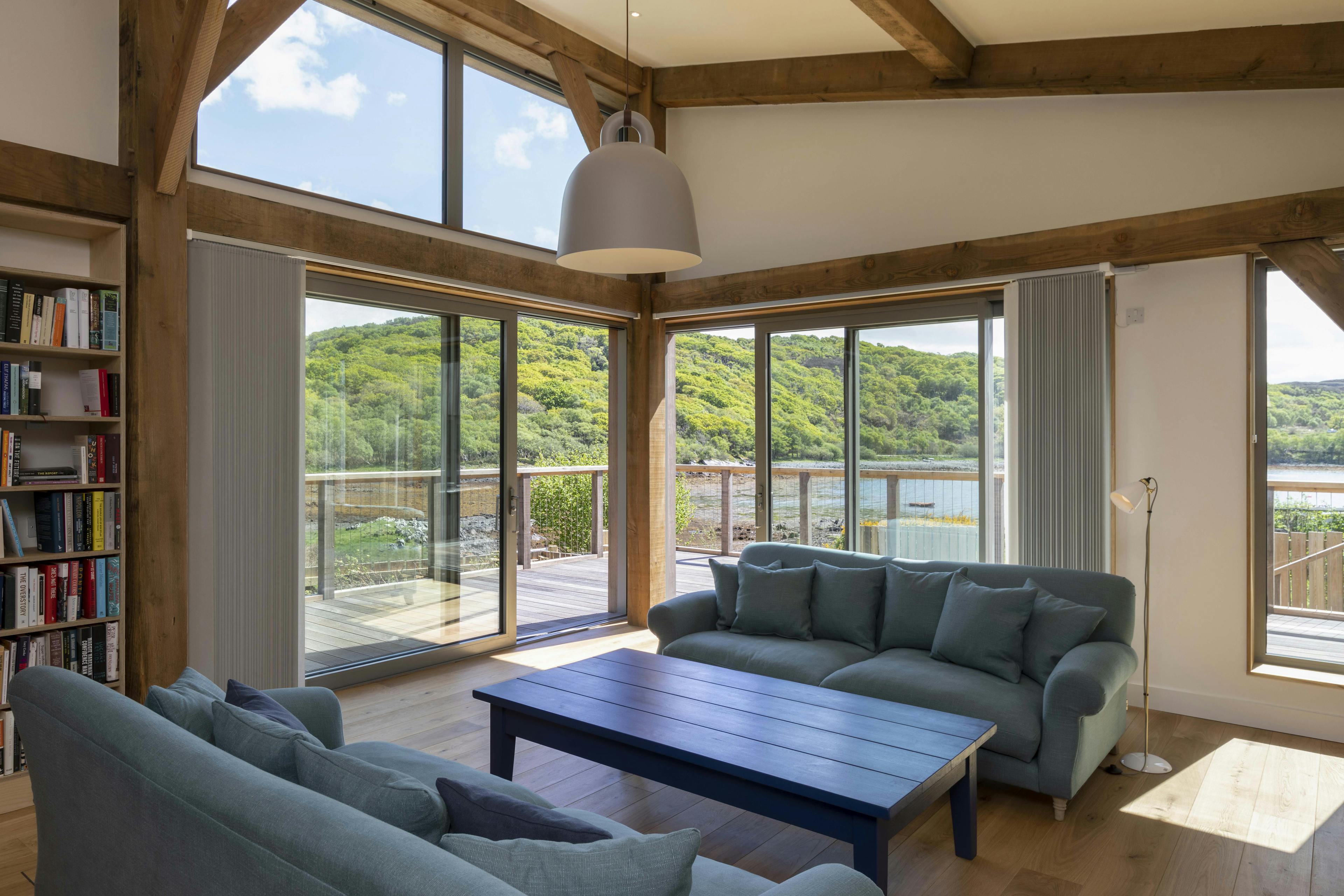 A living area with sofas under a Douglas fir framed mono pitched roof