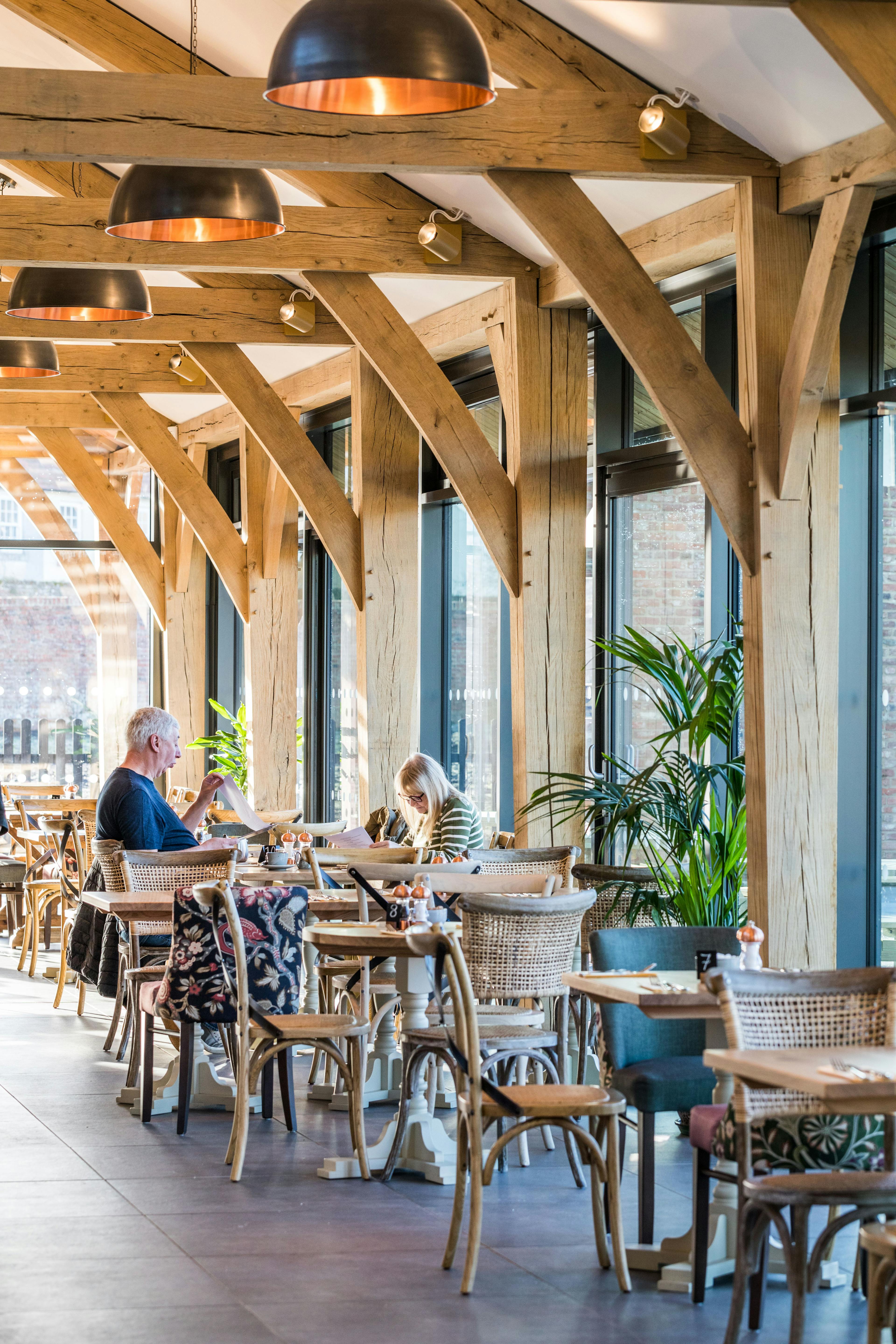 Internal image of an oak framed cafe with customers at a table and a waitress