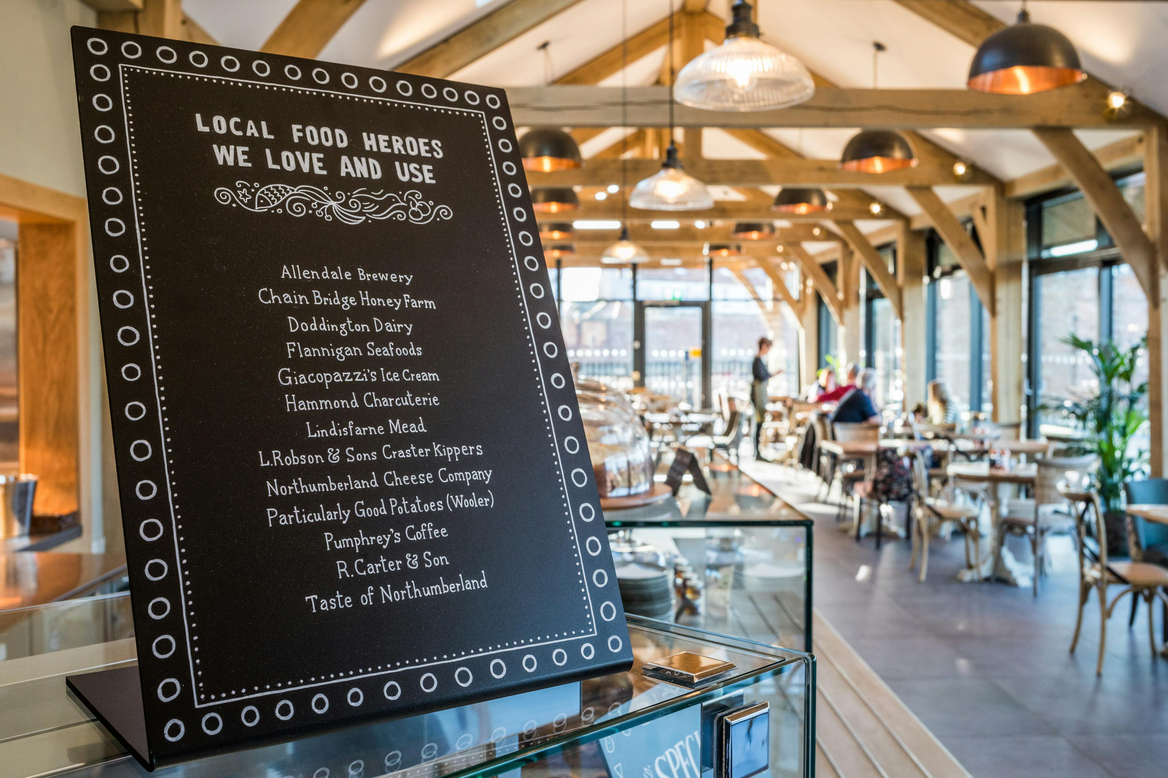 Internal image of an oak framed cafe with customers at a table and a waitress