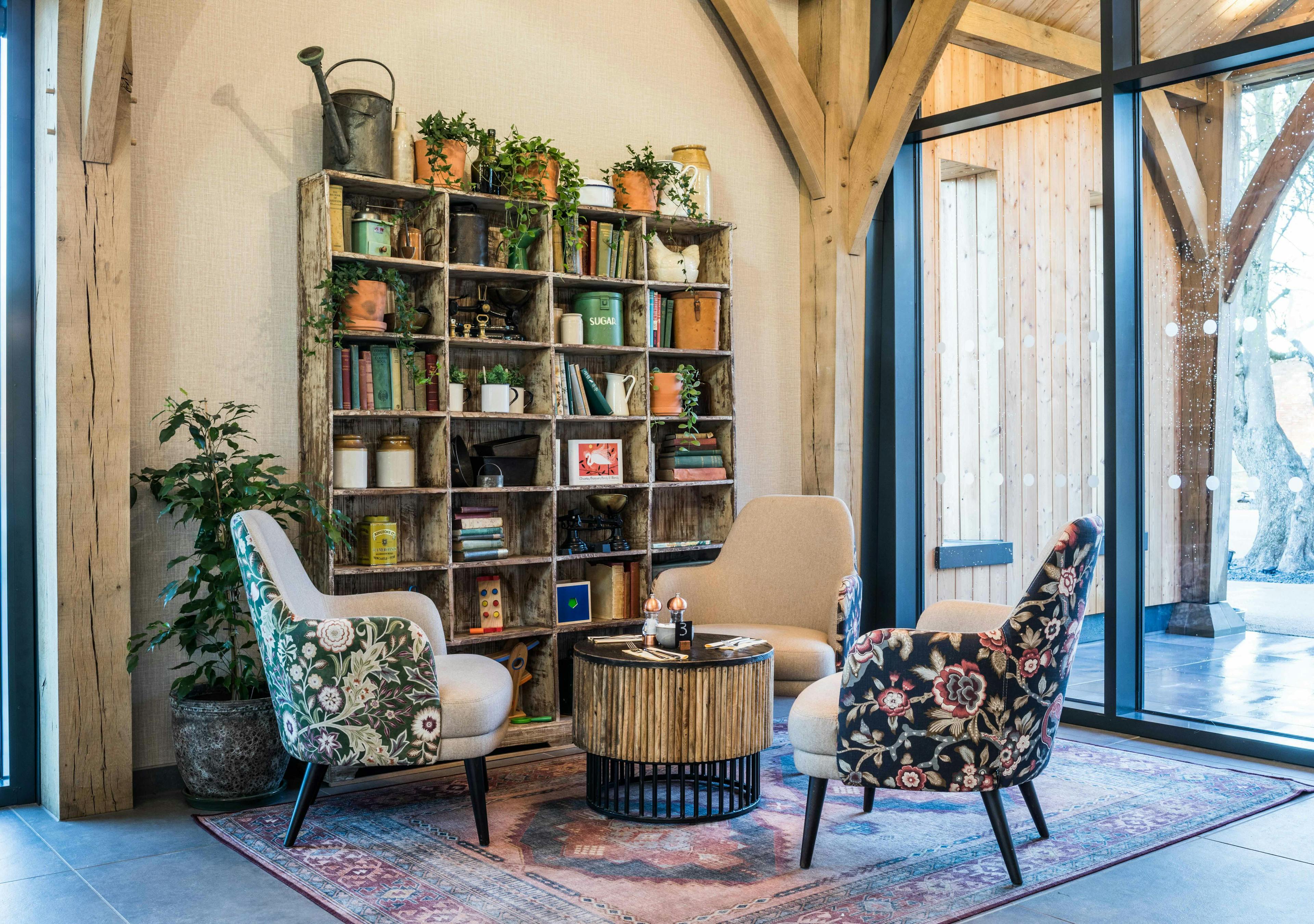 A corner of an oak framed cafe with armchairs and bookshelves