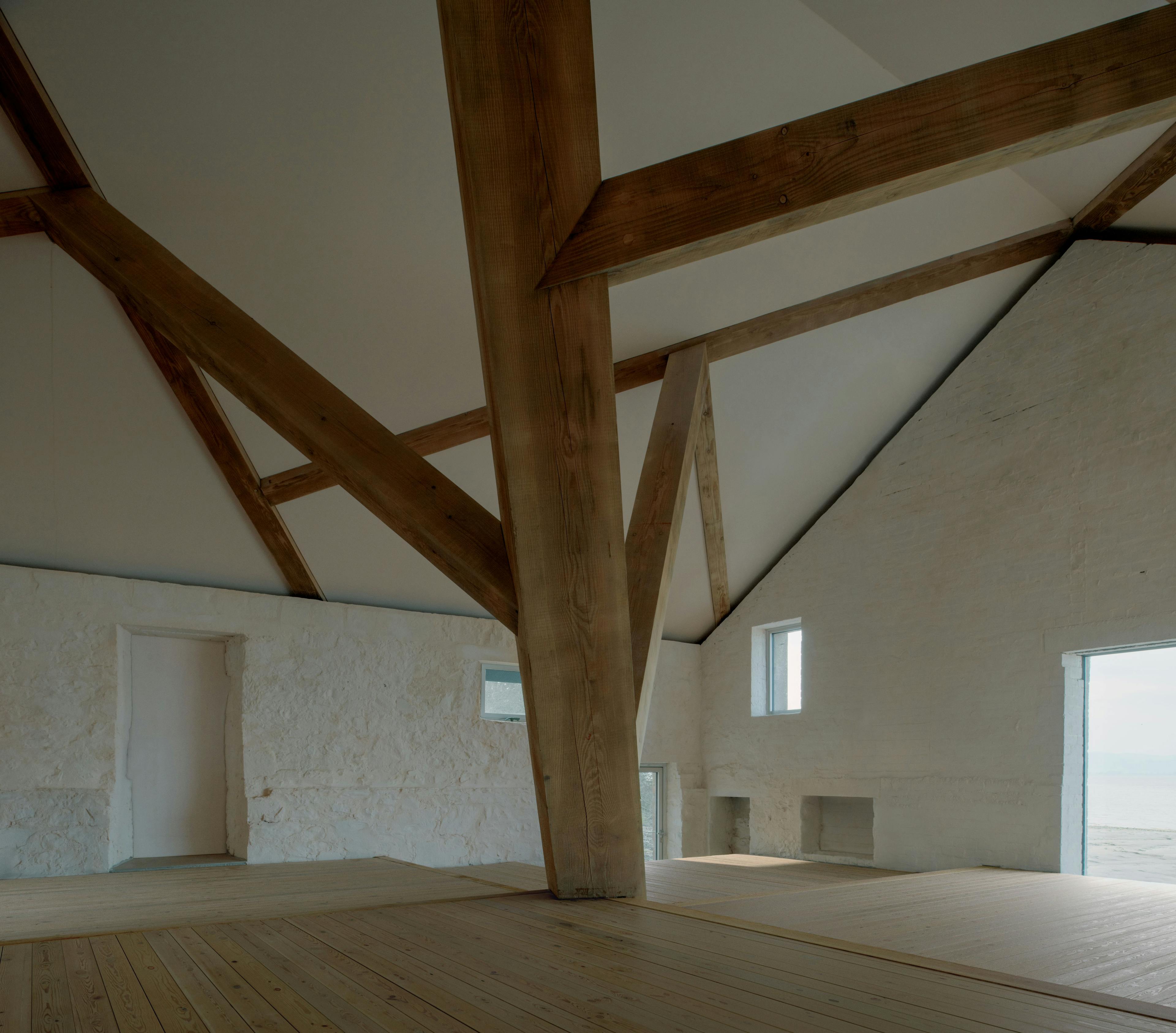 Interior of a riverside boathouse with a complex structural timber frame