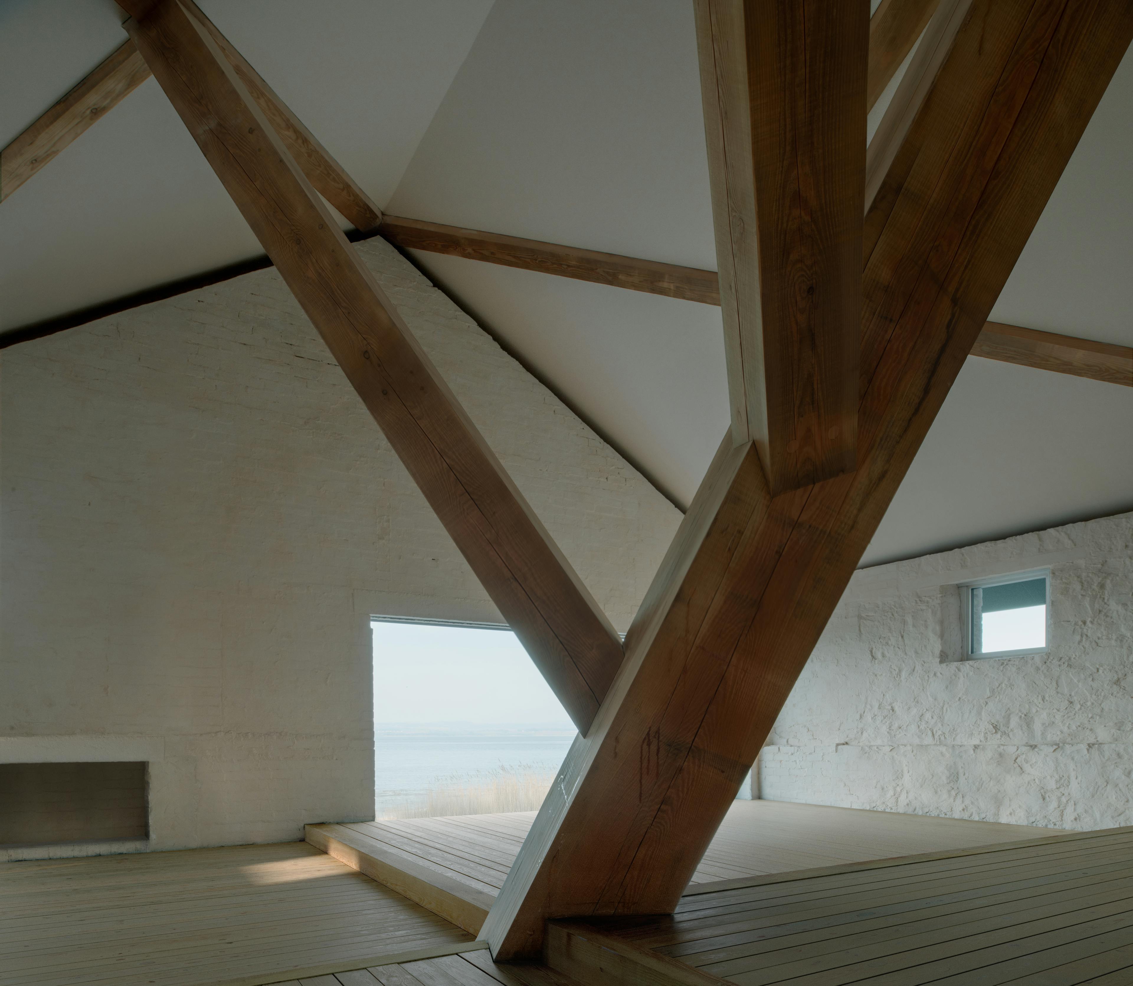 Interior of a riverside boathouse with a complex structural timber frame