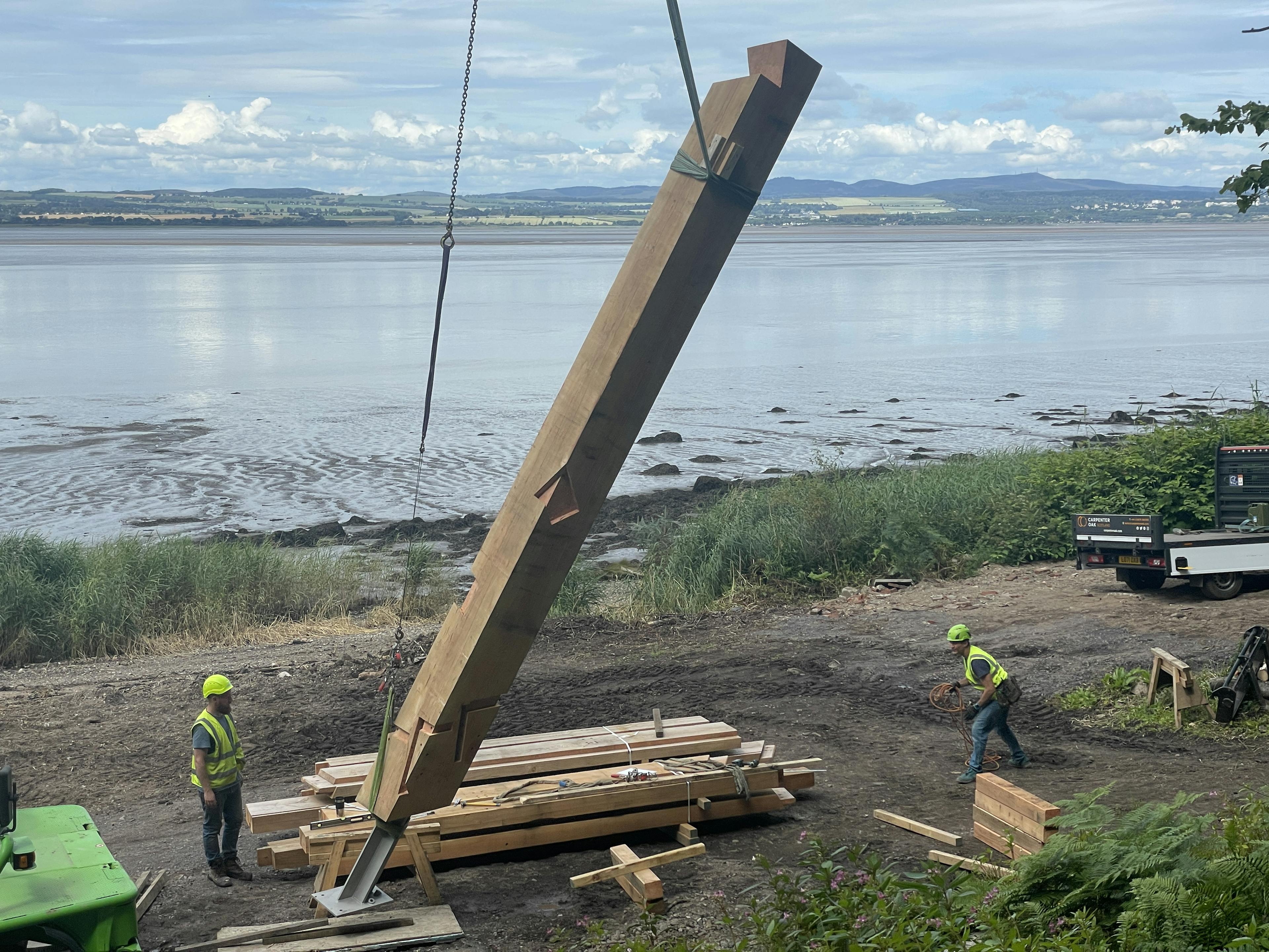 Crane lifting a central post into position during the installation of the Riverside Boathouse, with Douglas fir and larch timbers being assembled and secured using steel fixings