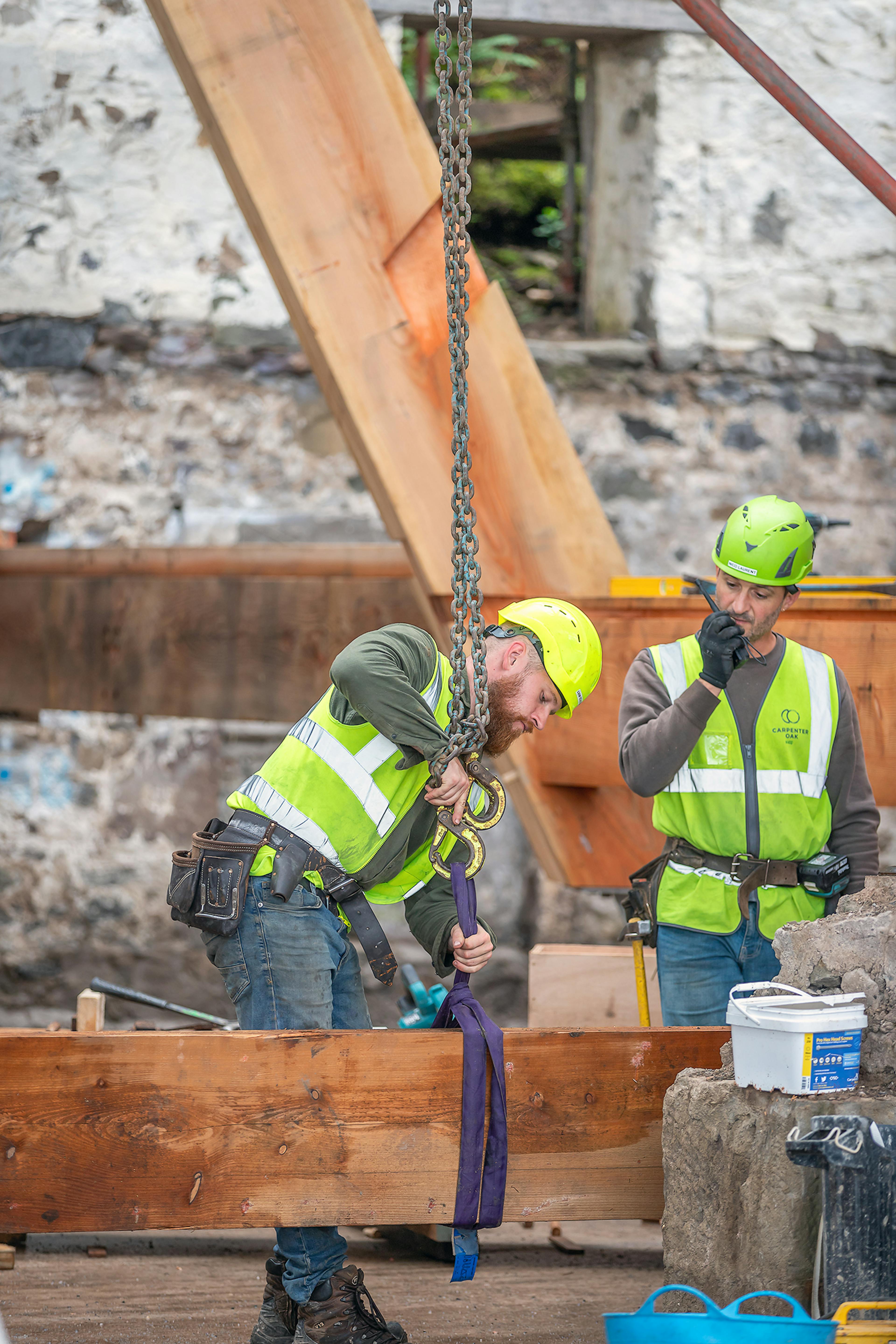 Carpenters lifting a central post into place during the on-site assembly of the Riverside Boathouse, constructed with Douglas fir and larch timbers