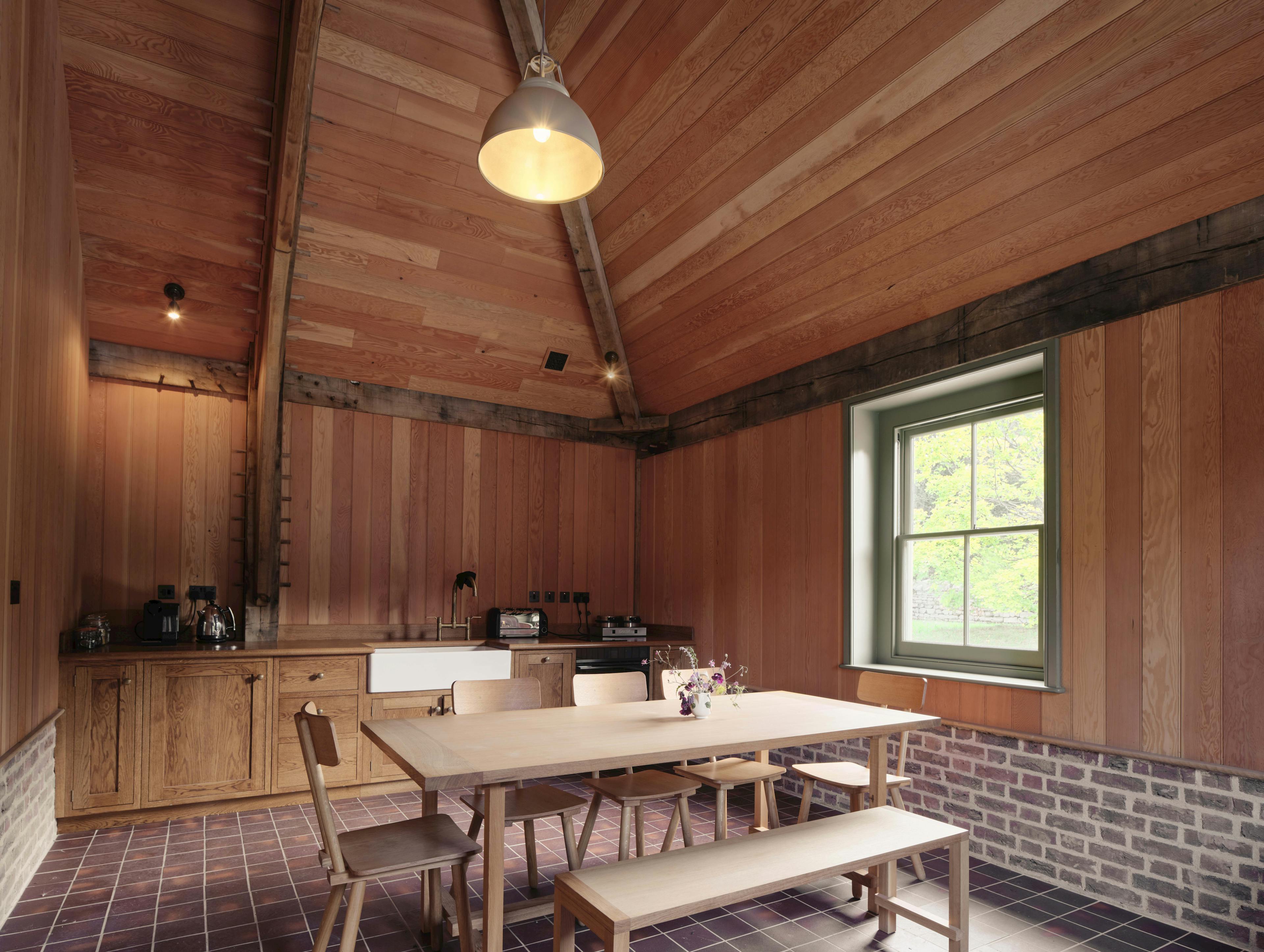 Interior of a traditional oak-framed barn featuring a compact, minimalist kitchen layout