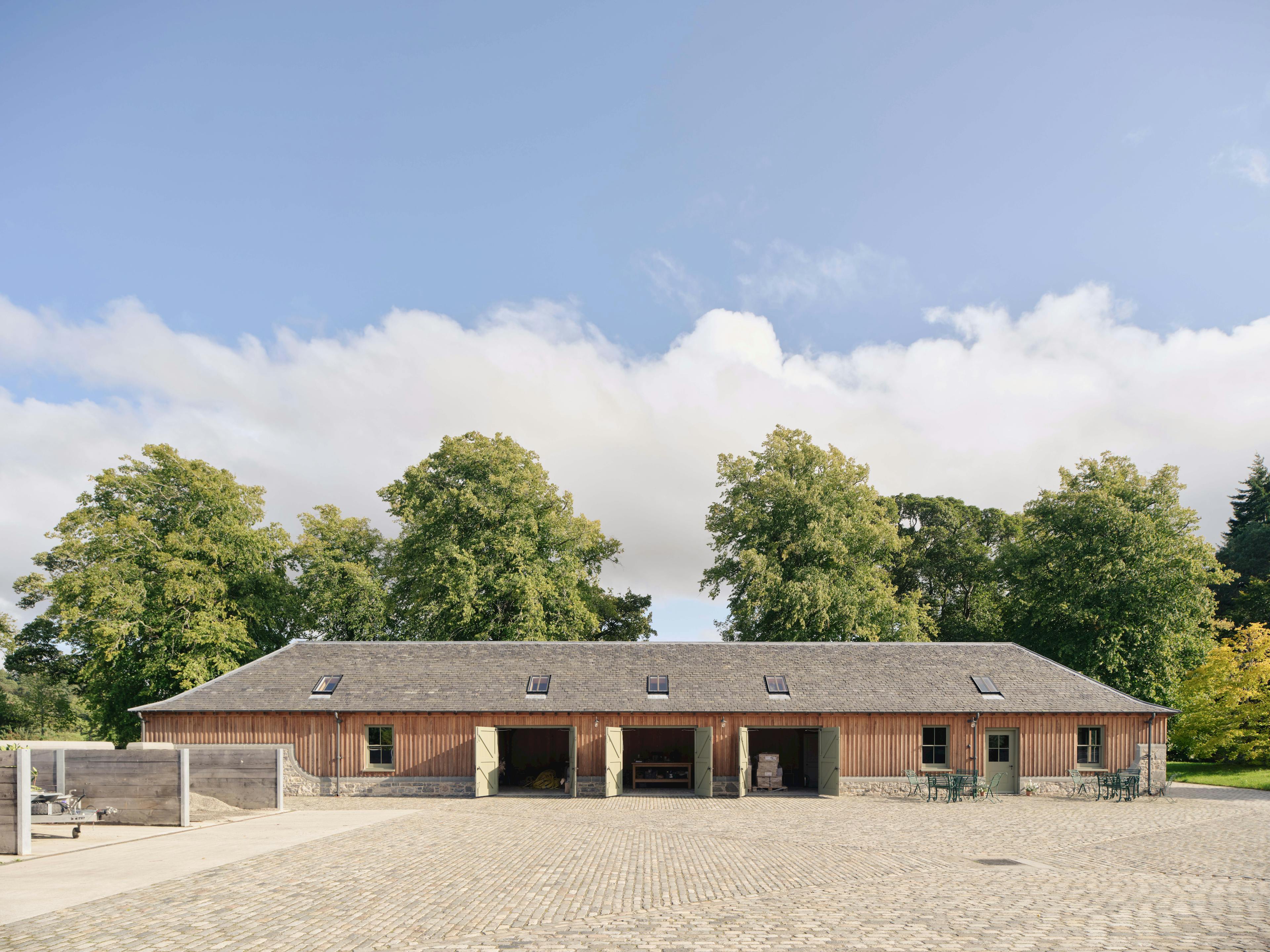 Home Farm Barns on the Aldourie Estate with doors open, revealing a multifunctional space with integrated seating and kitchen area