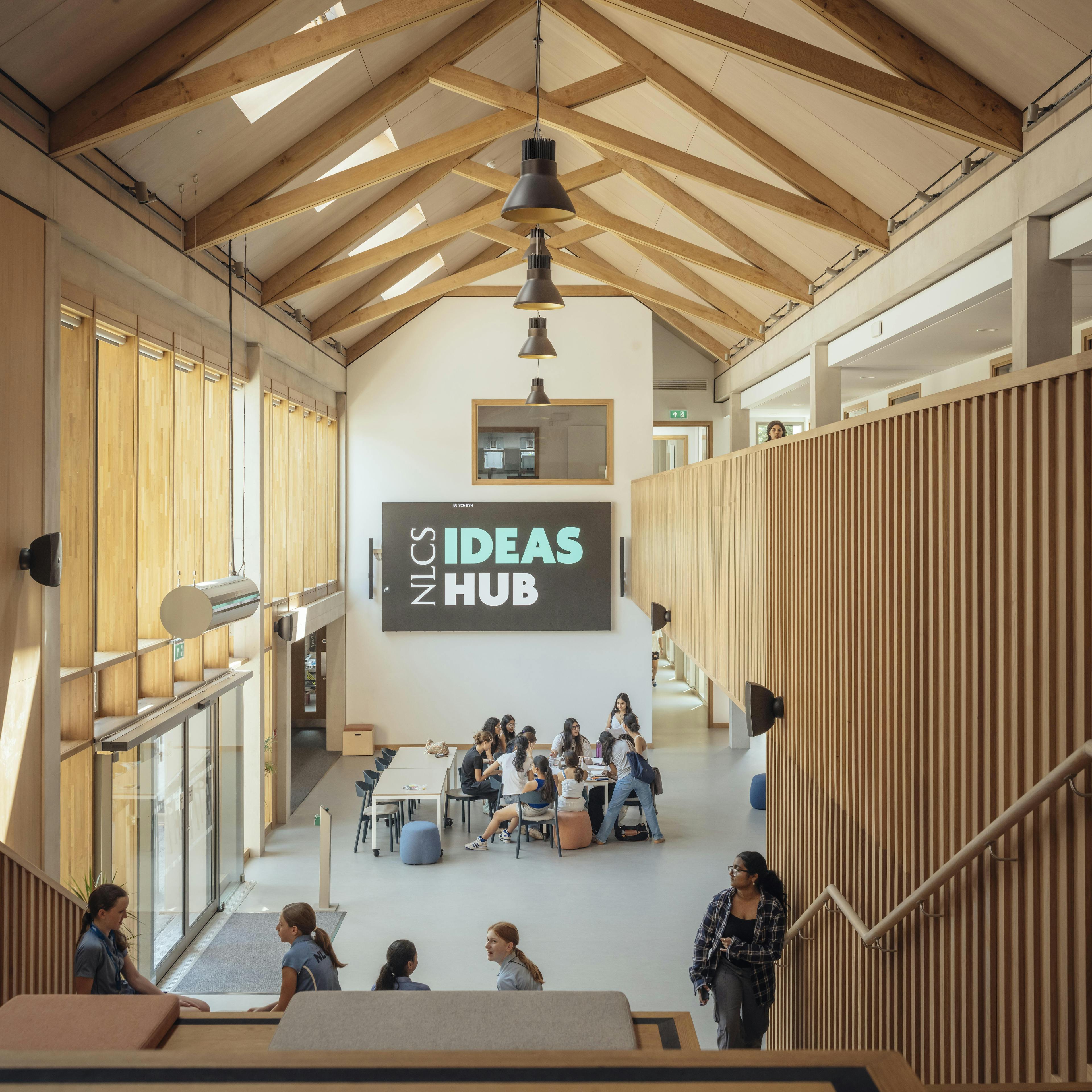School children in uniform inside a school building with striking oak trusses in the roof