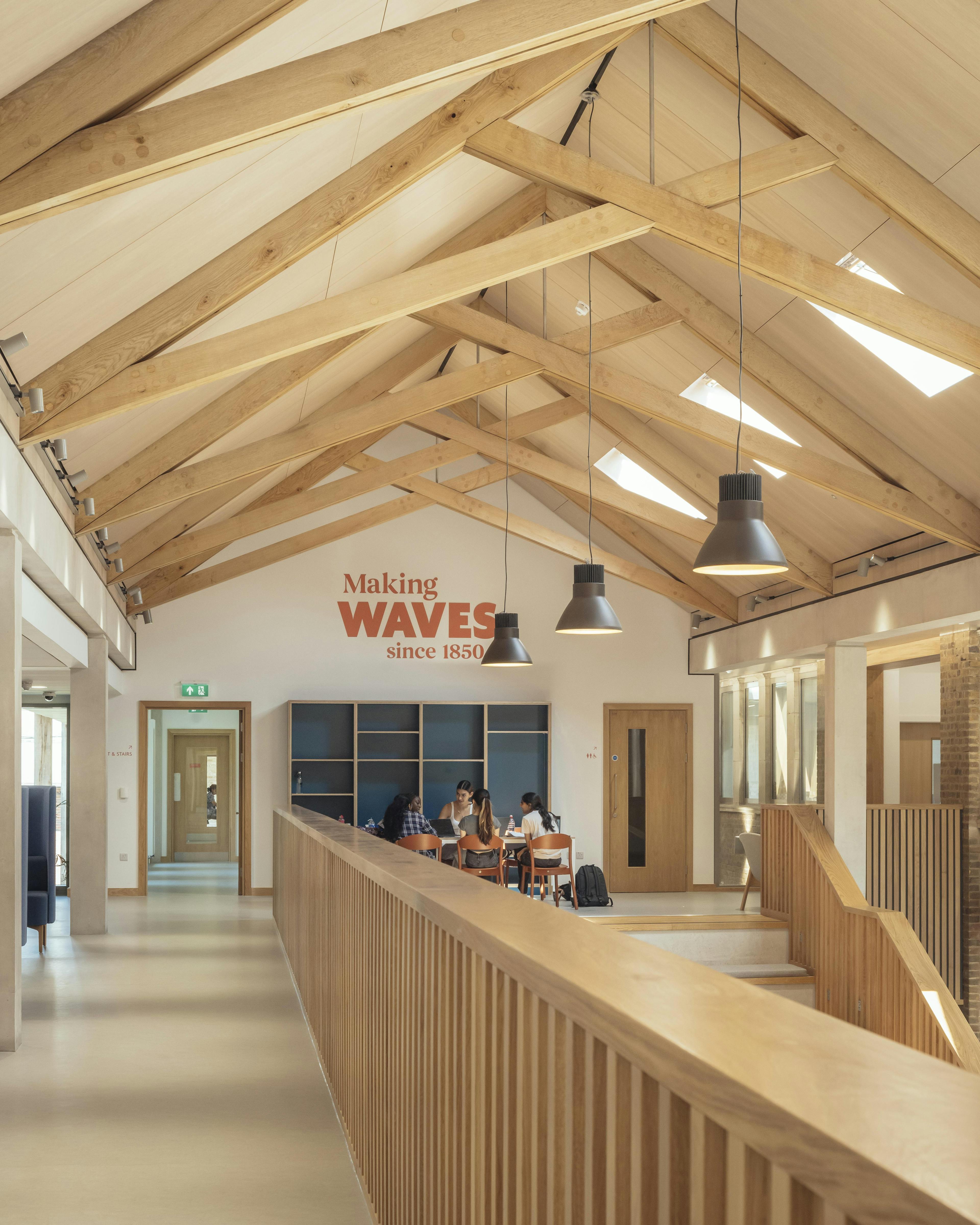 School children in uniform inside a school building with striking oak trusses in the roof
