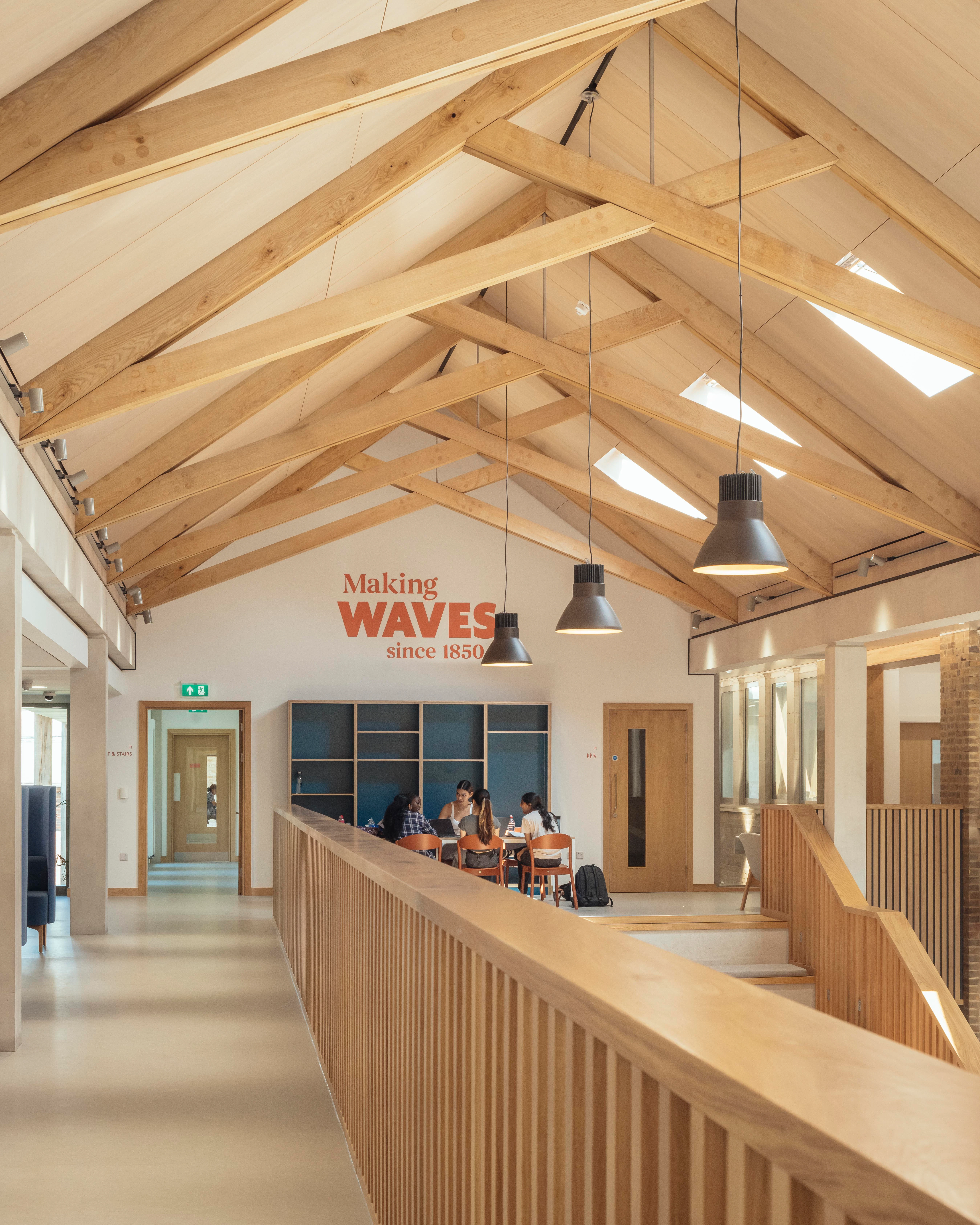 School children in uniform inside a school building with striking oak trusses in the roof
