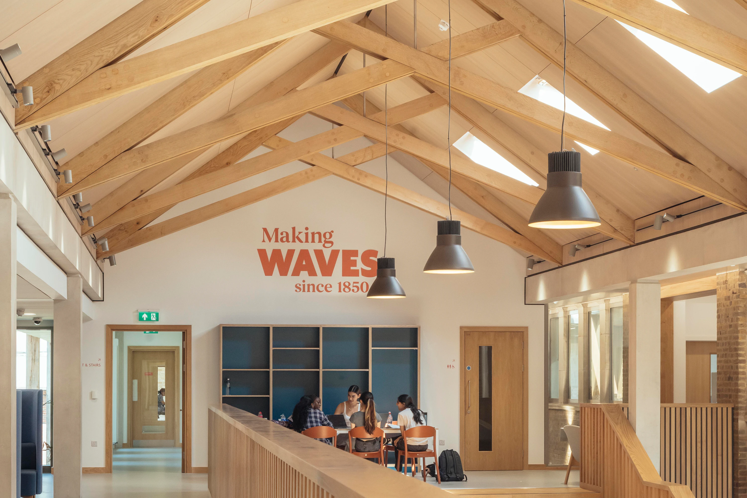 School children in uniform inside a school building with striking oak trusses in the roof