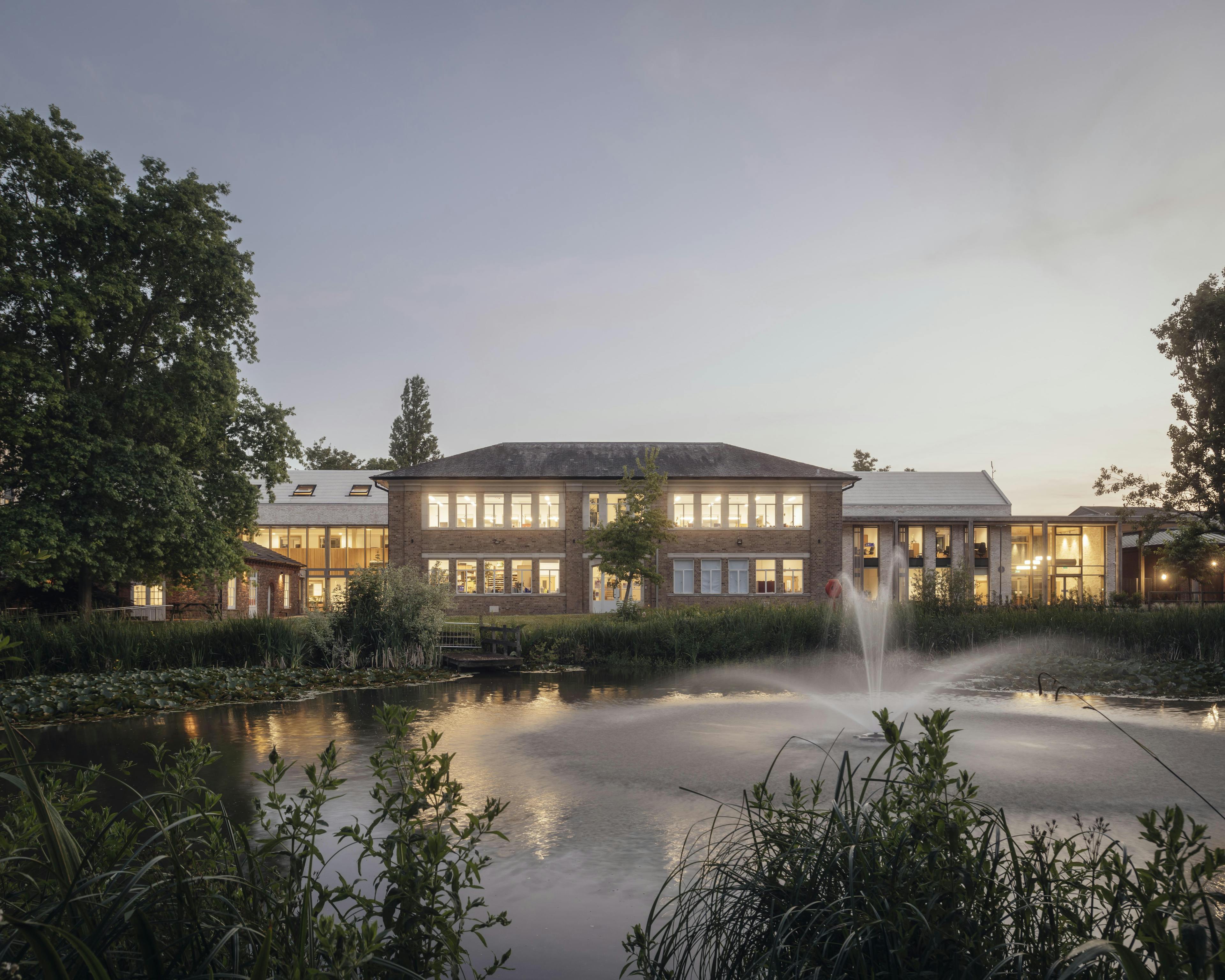 A school building at dusk with lights shining from the windows