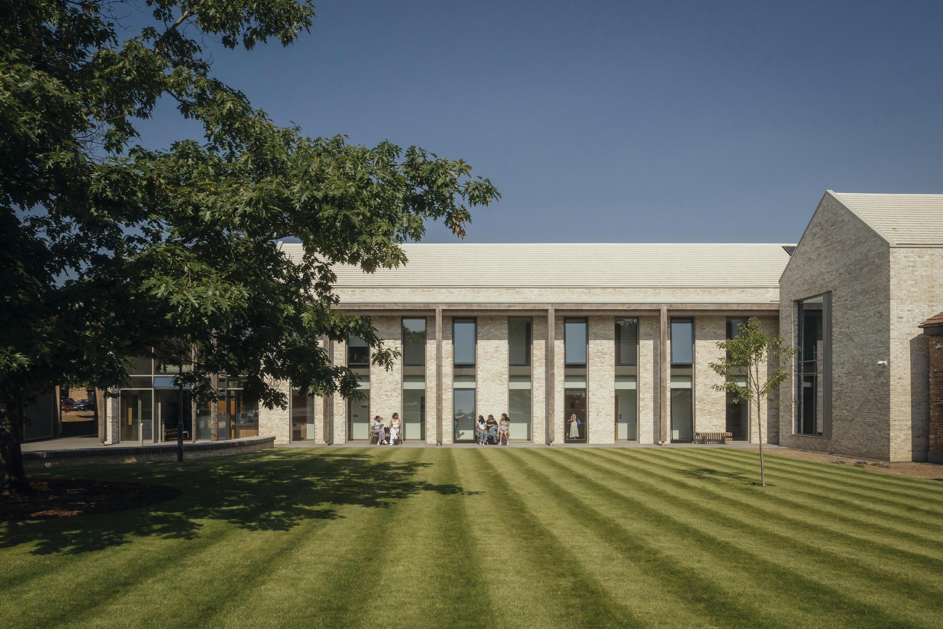 A school building with an oak pergola and green lawn in front of it