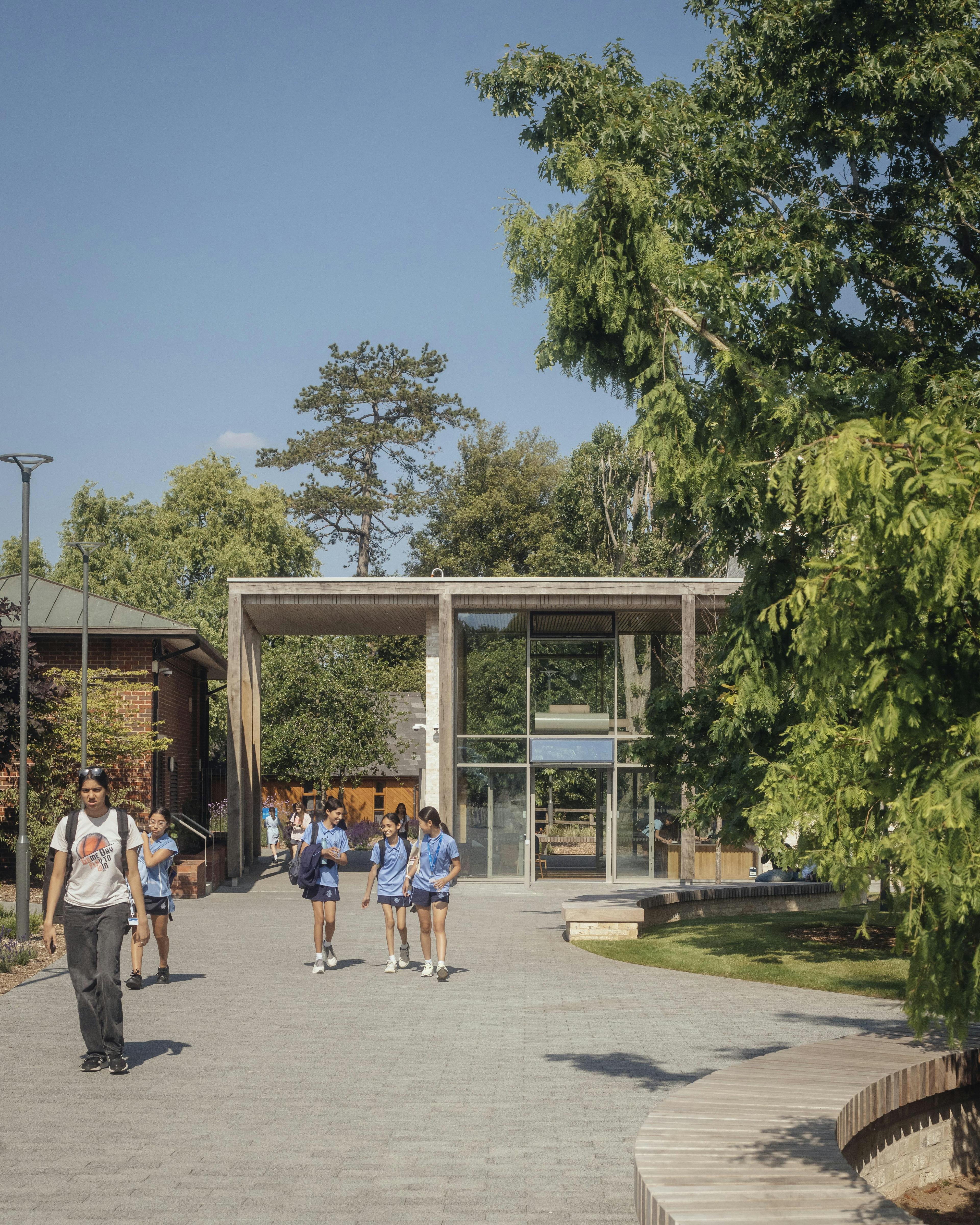 School children in uniform outside a school building with an oak pergola