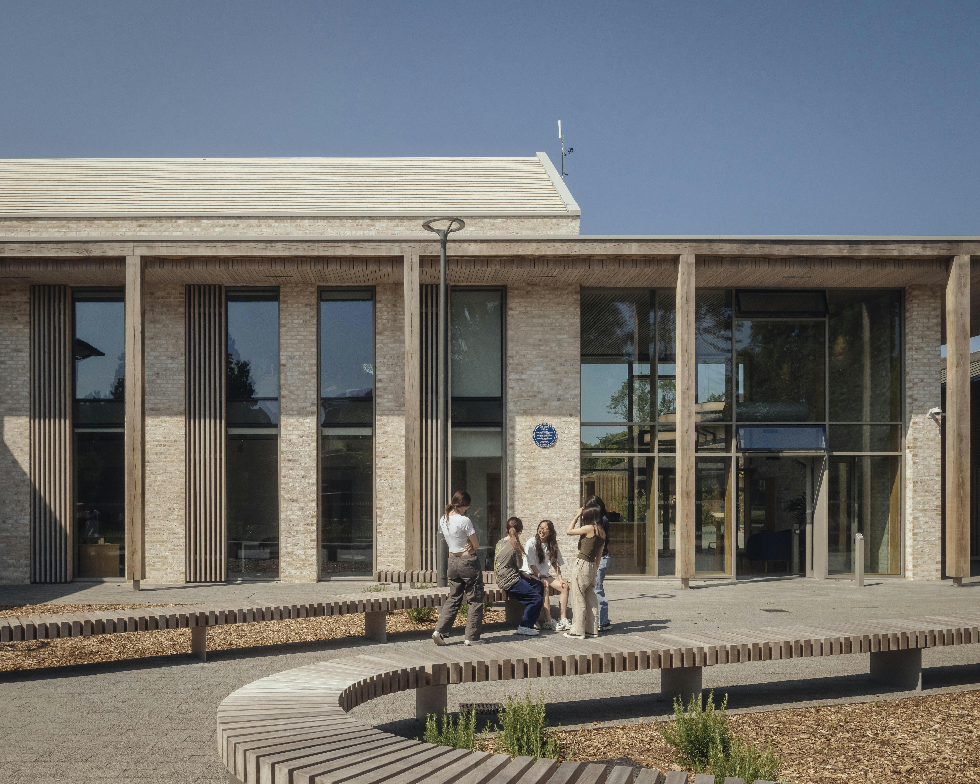 School children in uniform outside a school building with an oak pergola