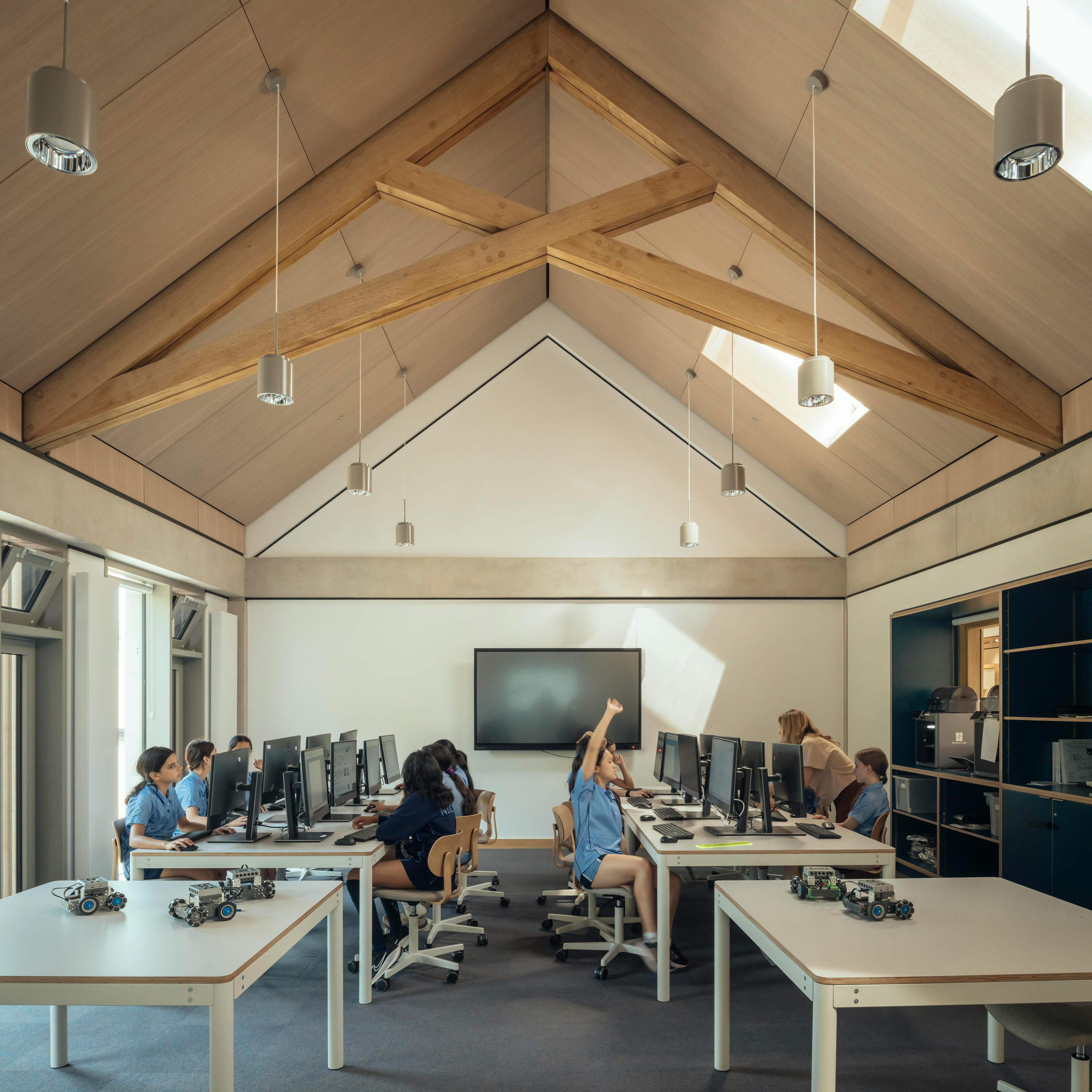 School children in uniform inside a school classroom with striking oak trusses in the roof