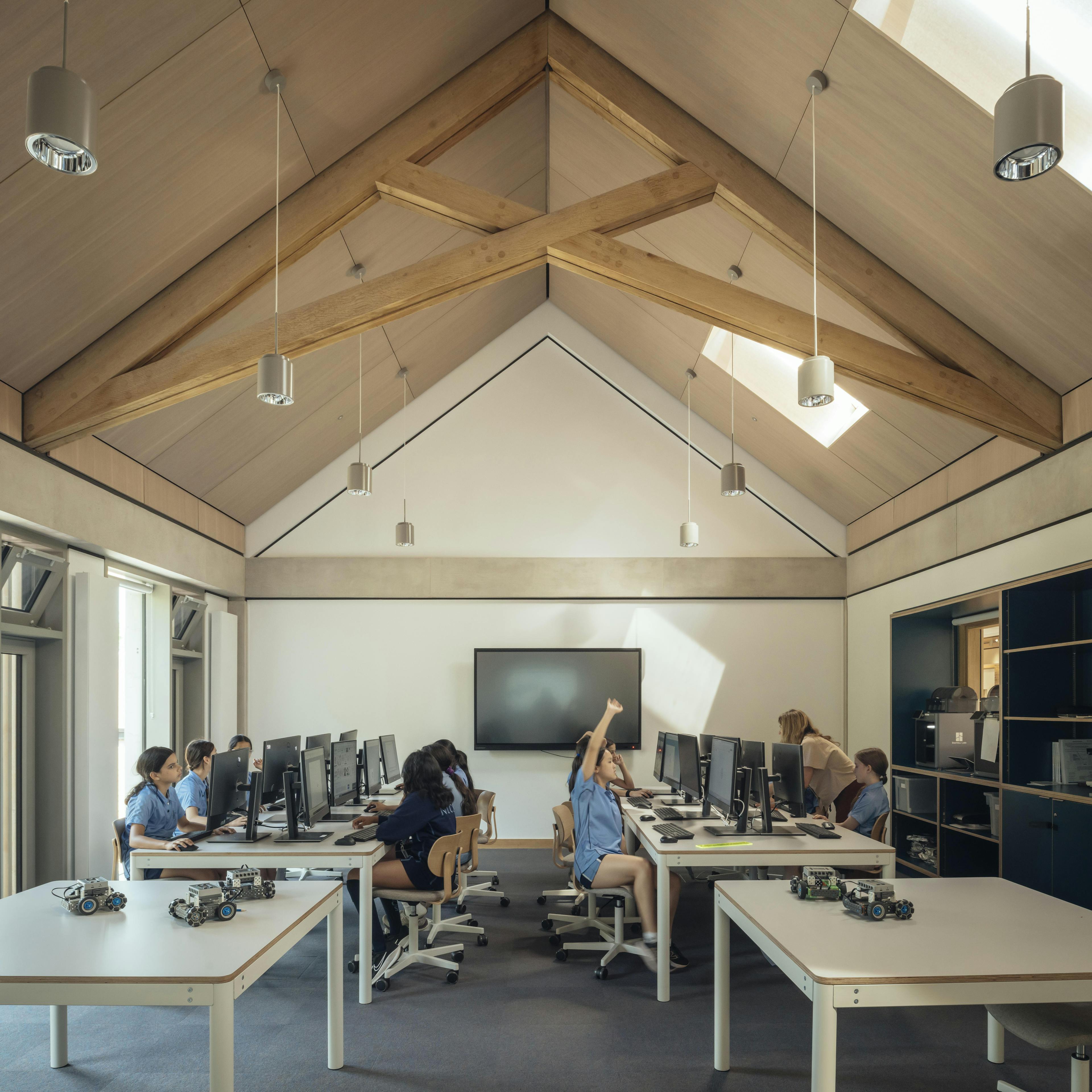 School children in uniform inside a school classroom with striking oak trusses in the roof