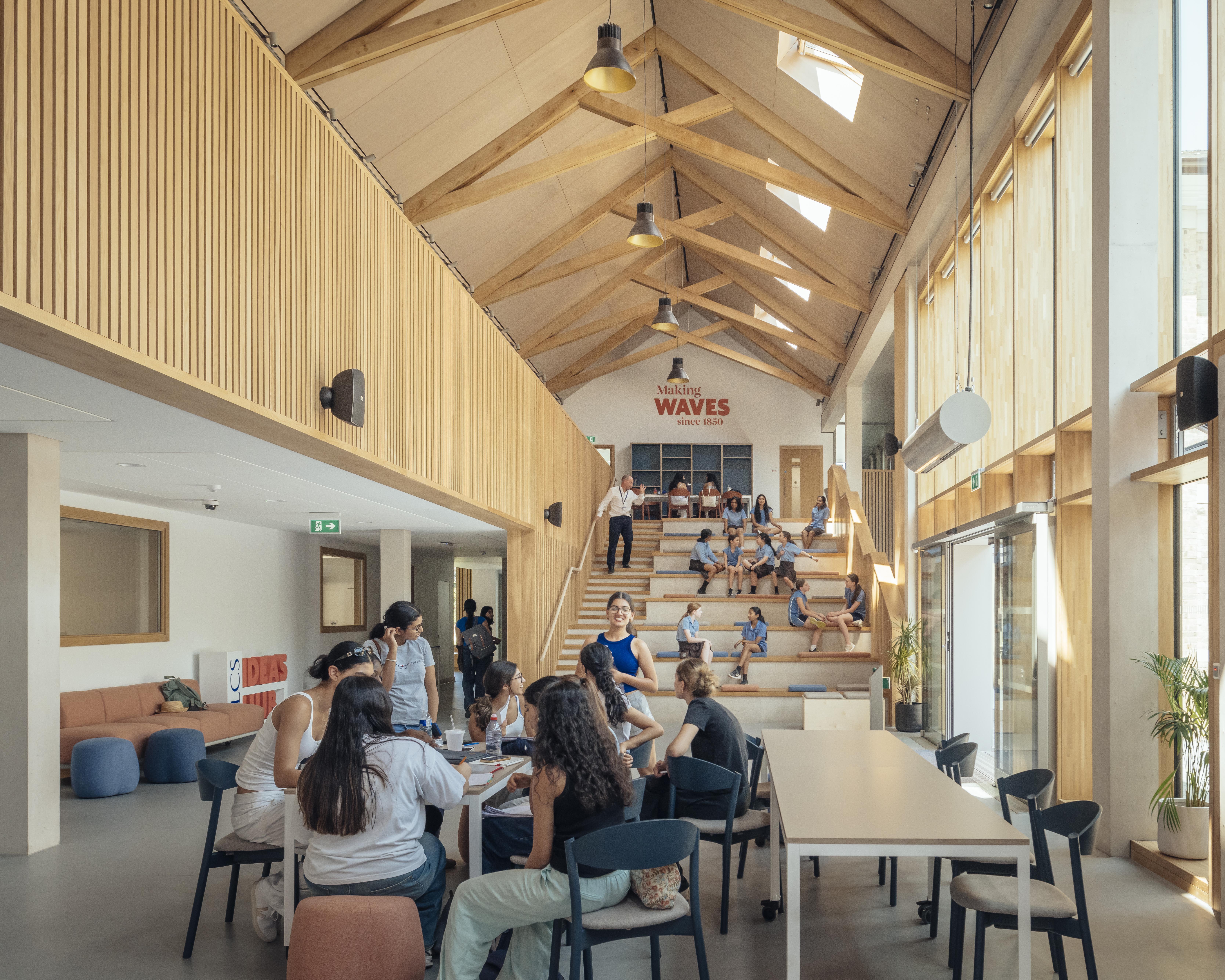 School children in uniform inside a school building with striking oak trusses in the roof