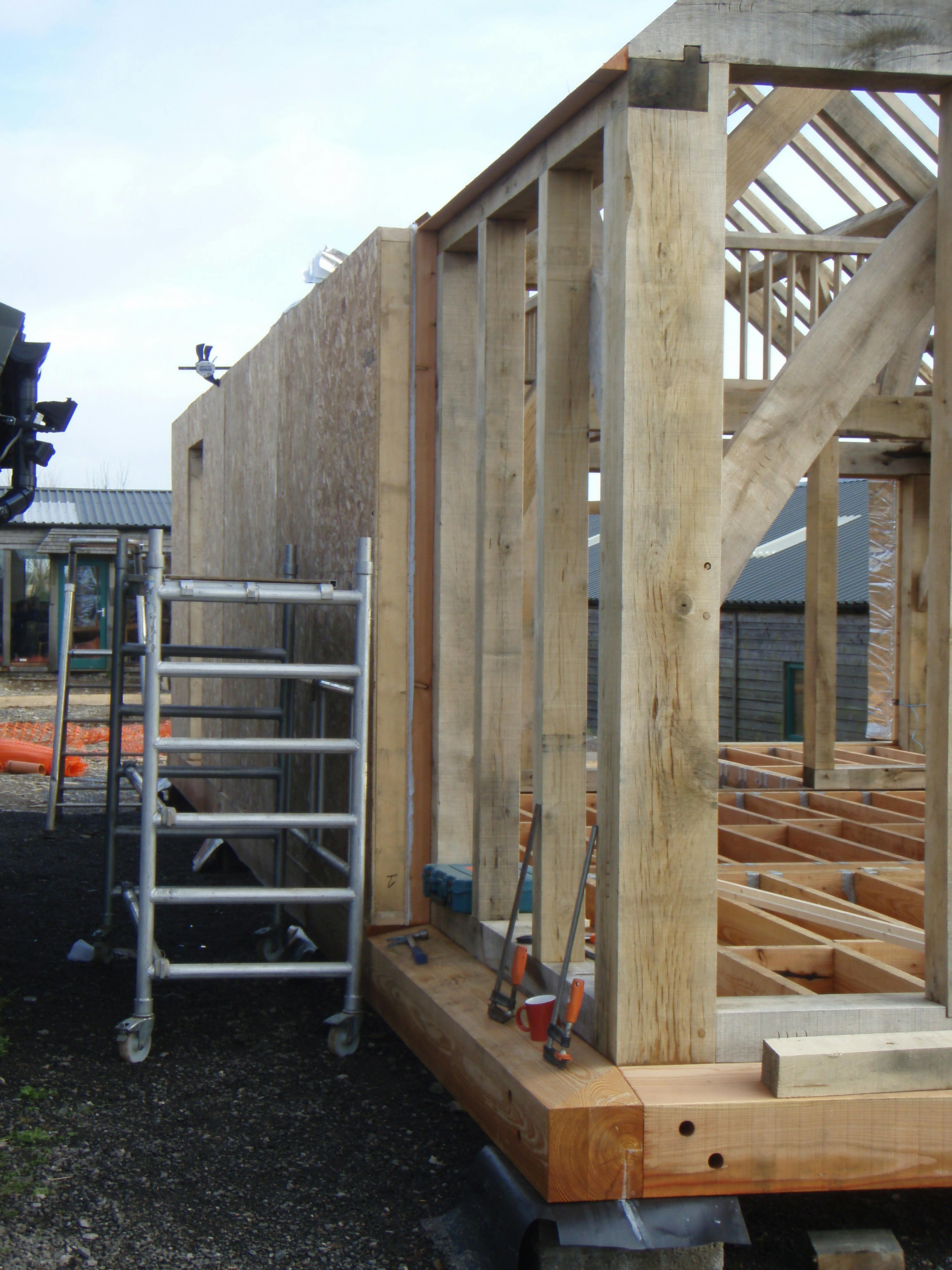 Structural insulated panels (SIP) being wrapped at the Carpenter Oak show barn in East Cornworthy, illustrating the construction process and timber frame integration