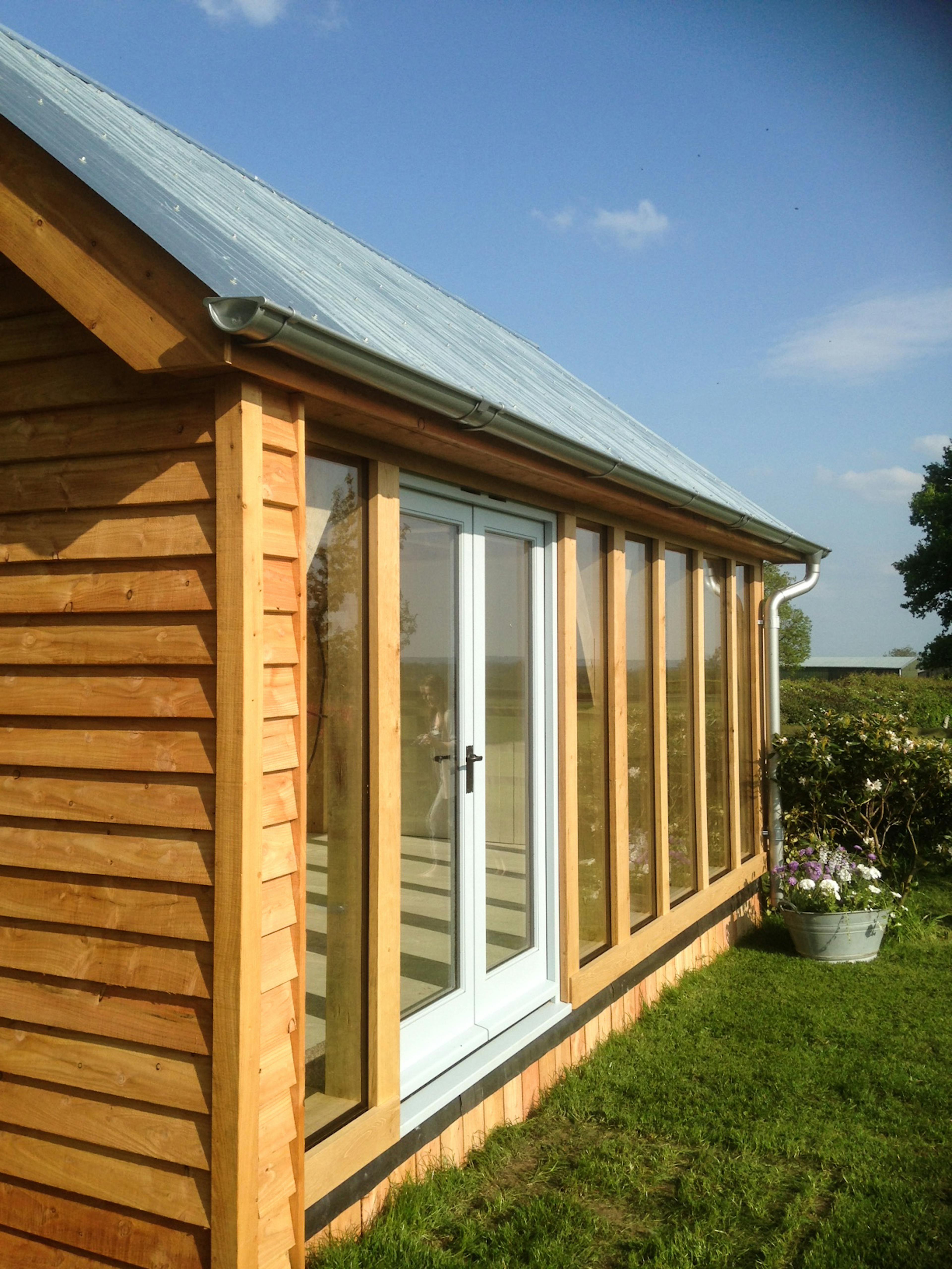 Finished oak timber frame of a small cabin with glazing installed, showcasing exposed beams and precise craftsmanship.