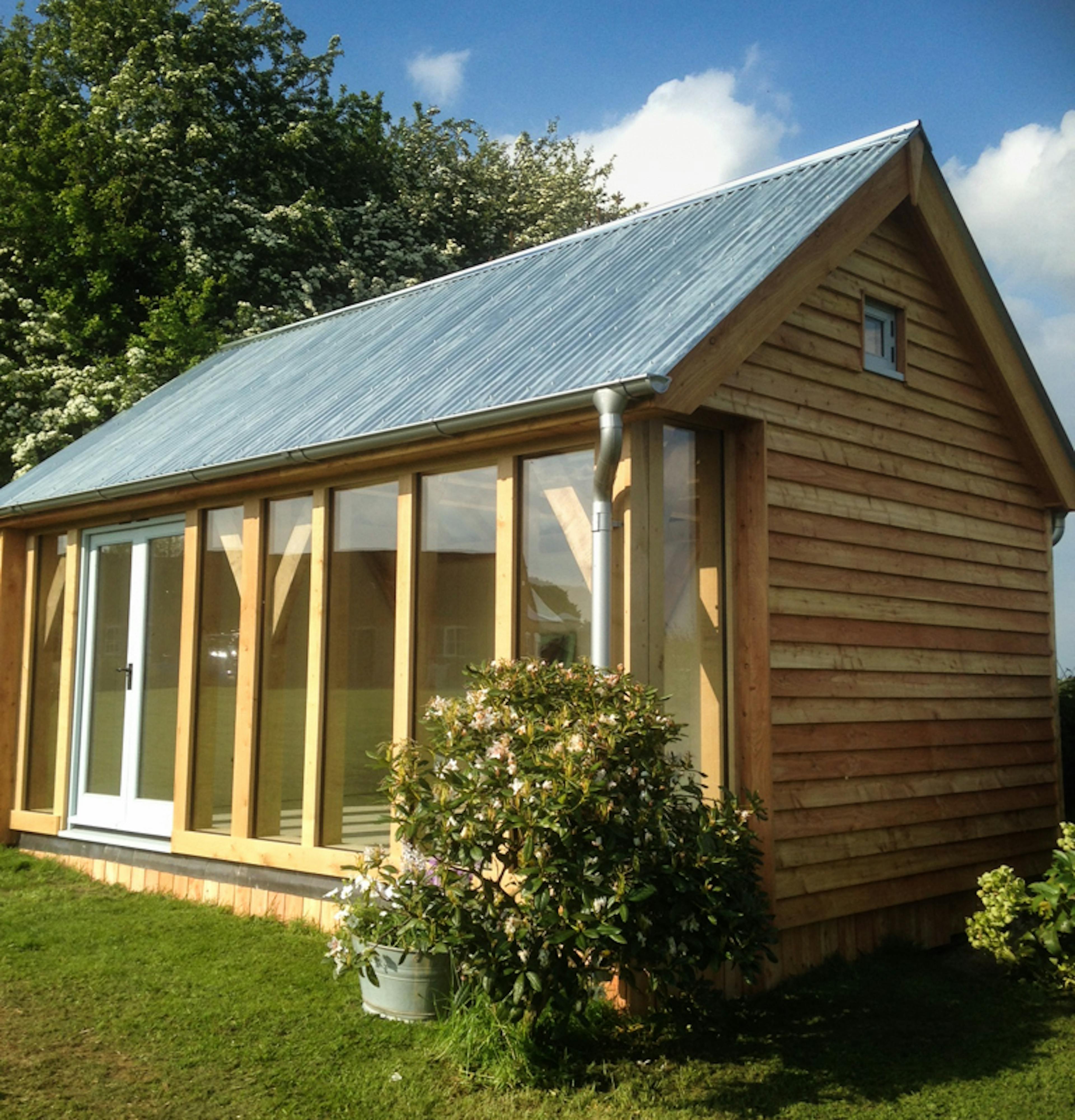 Finished oak timber frame cabin designed by LifeSpace Architects, with glazing installed, showcasing exposed beams and detailed craftsmanship.
