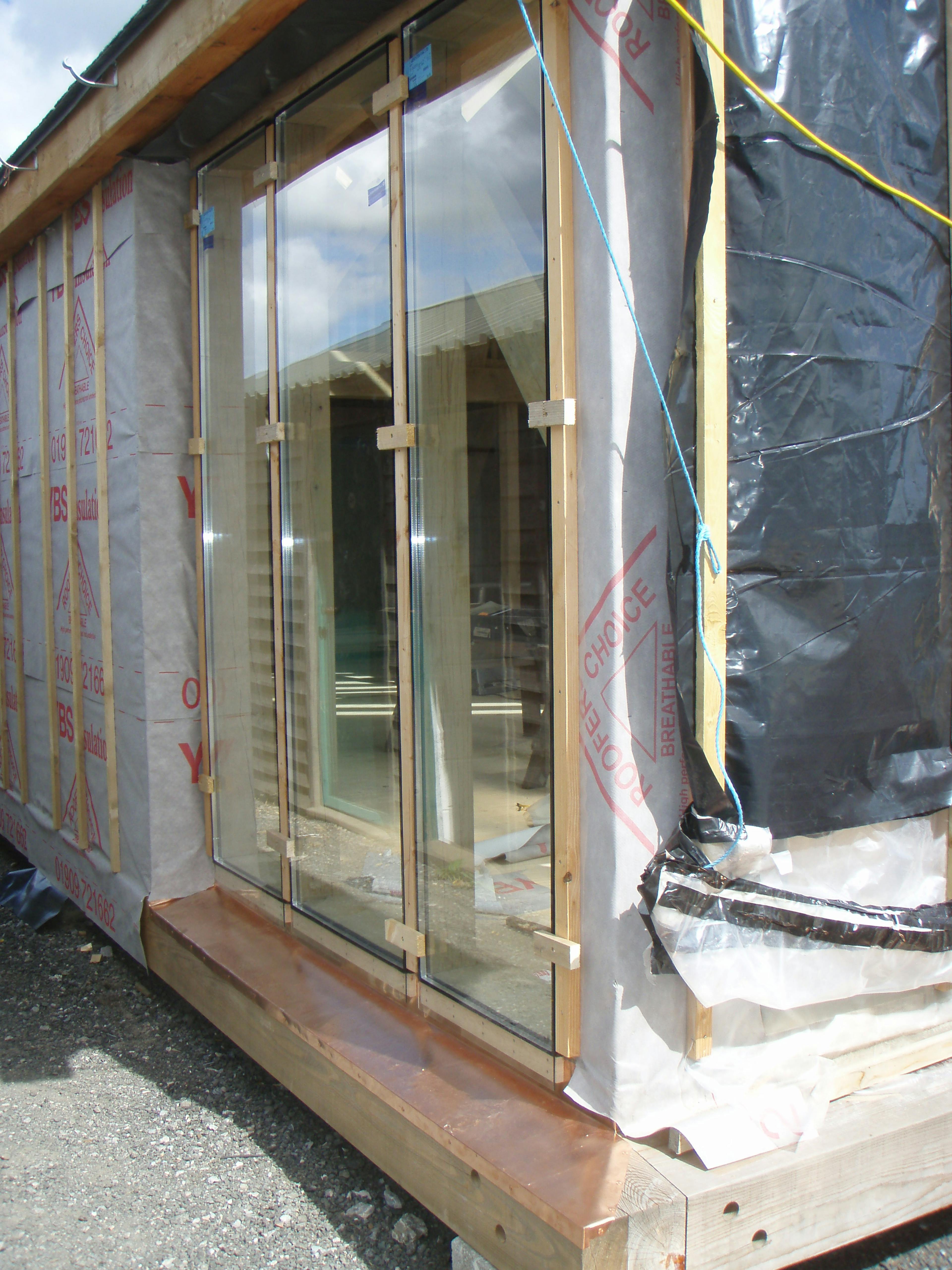 Direct glazing installation at the Carpenter Oak show barn in East Cornworthy, highlighting precise fitting, timber frame structure, and craftsmanship