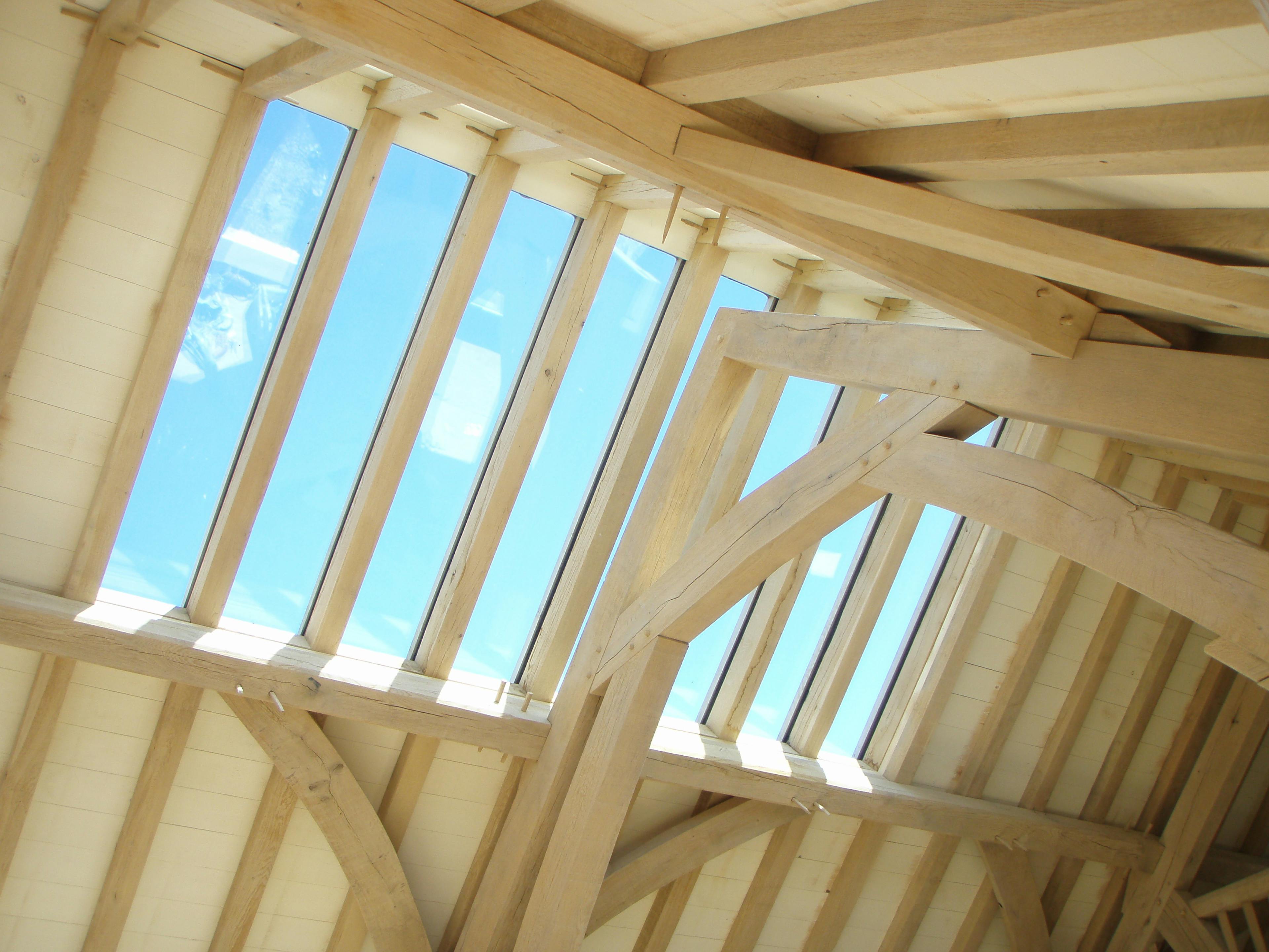 Internal direct glazing installed within the oak timber frame of the Carpenter Oak show barn in East Cornworthy, highlighting precise joinery, exposed beams, and craftsmanship