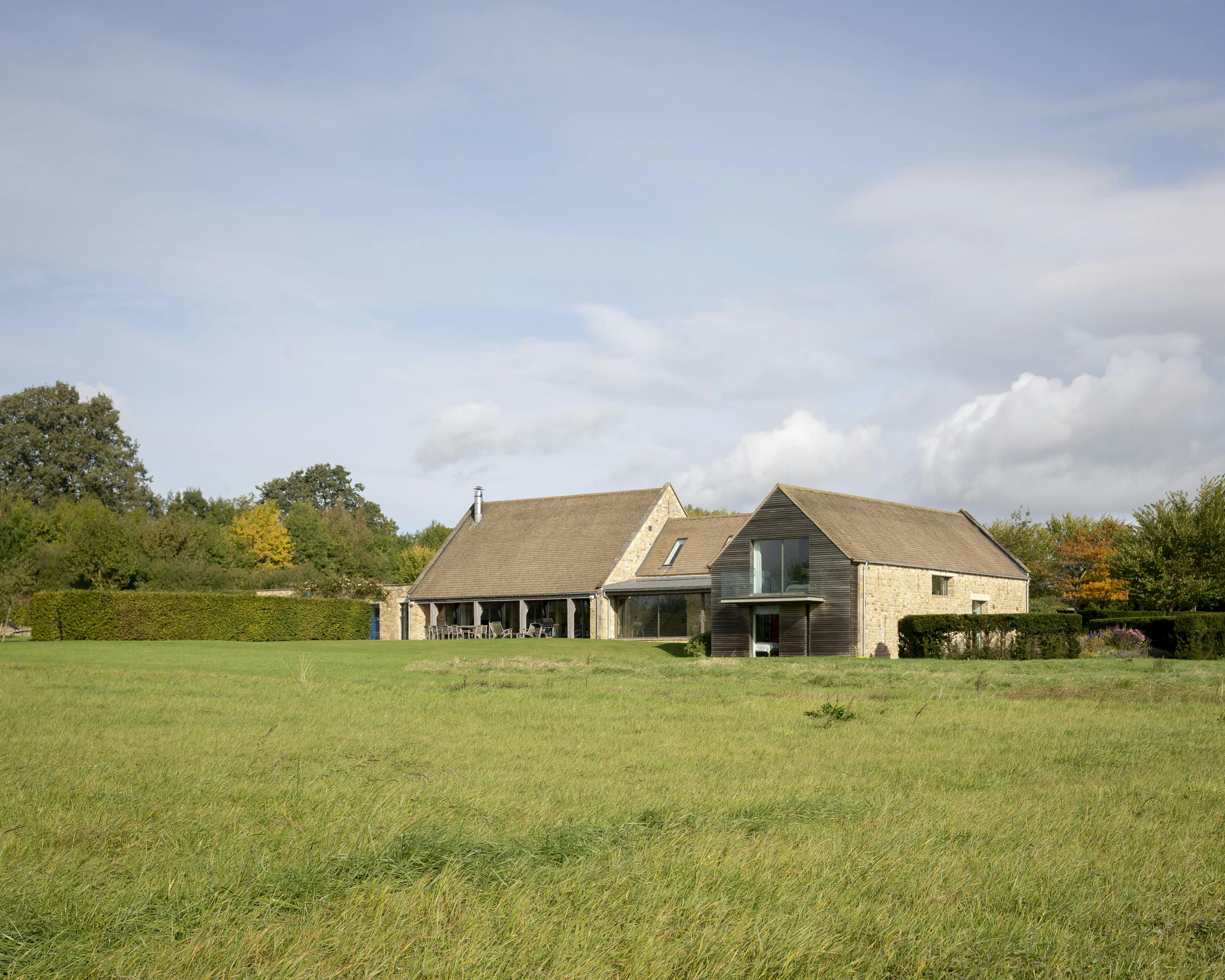Exterior view of a renovated stone barn with a modern cladded extension